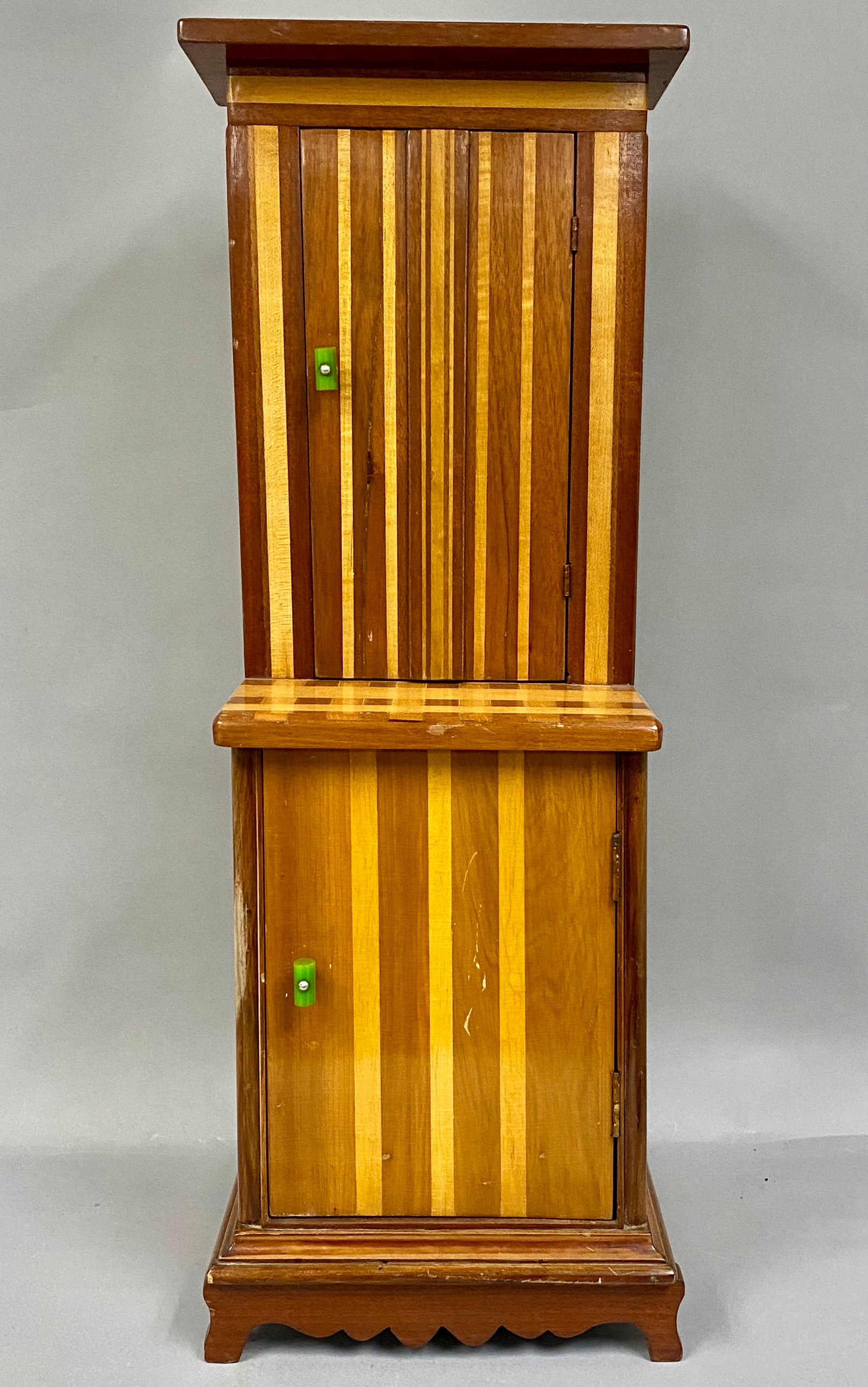 Small Art Deco Mixed-Wood Step-Back Cupboard: Circa 1930s, Small tall step-back cupboard, likely crafted as an artisan piece, salesman sample, or child's furnishing. The cabinet is fitted with distinctive, faceted bright green pulls are likely