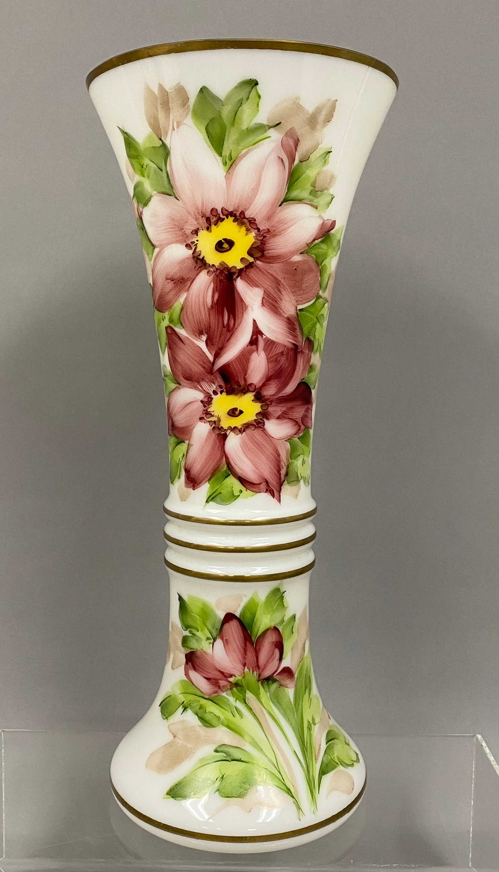 Large DeLuxe Hand Painted Vase: DeLuxe Inc. produced this large trumpet-form vase featuring hand-painted floral motifs in burgundy and pink by artist P. Ronnin. The opaque white milk glass body is accented with horizontal gold