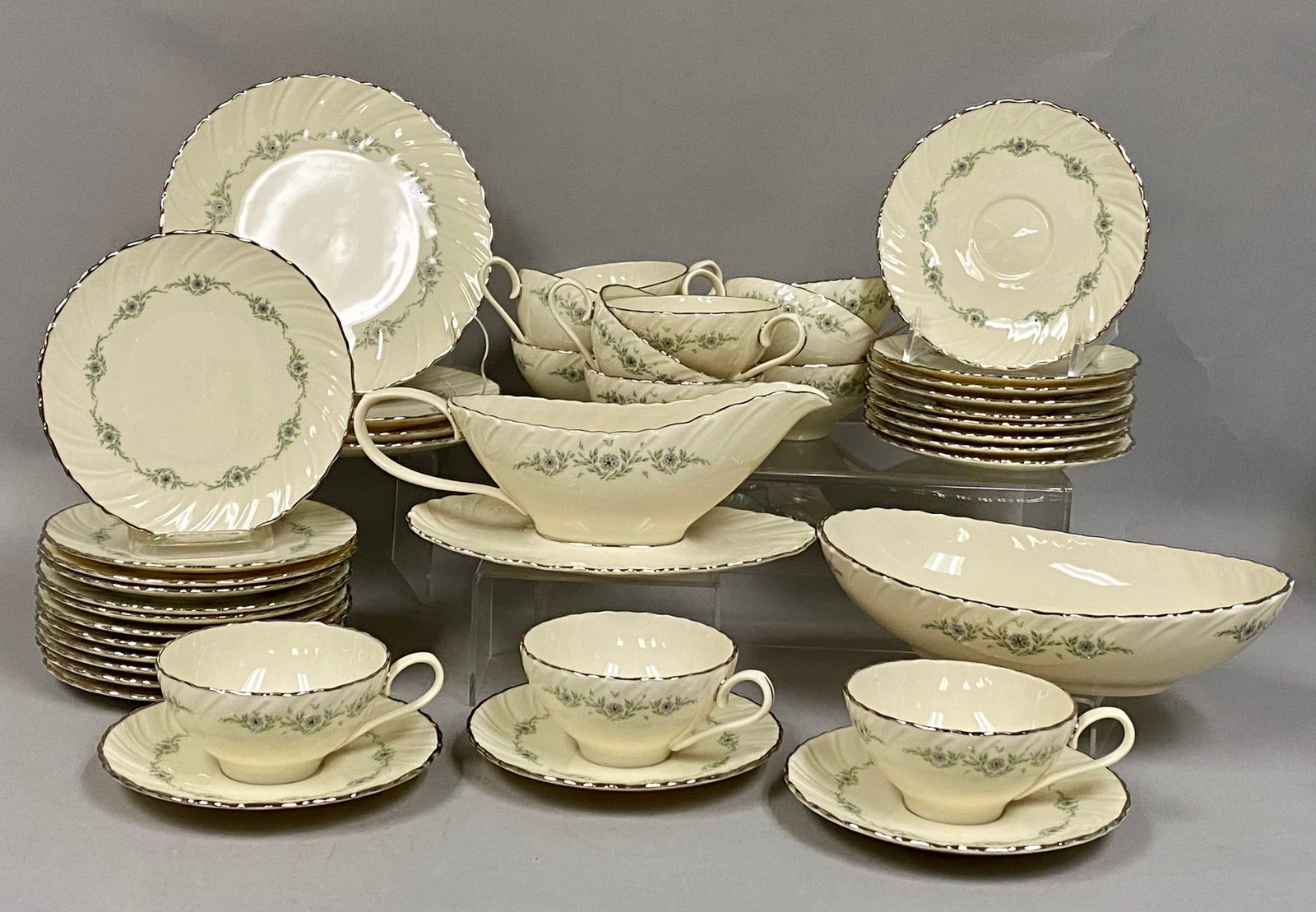 30pc Collection of Lenox Musette China: 30 piece set of Lenox ivory porcelain dinnerware in the Musette pattern, characterized by a spiral-fluted texture and a wreath of blue-gray flowers with green leaves. Each piece is accented by
