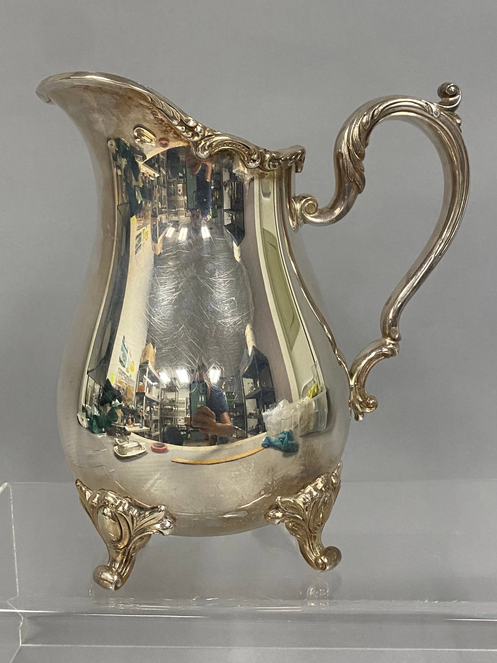 Webster Wilcox Silver-Plated Water Pitcher: This silver-plated pitcher was produced by the International Silver Company under the Webster Wilcox mark. The vessel is designed in the Rococo Revival style, featuring a scalloped shell-molded rim,