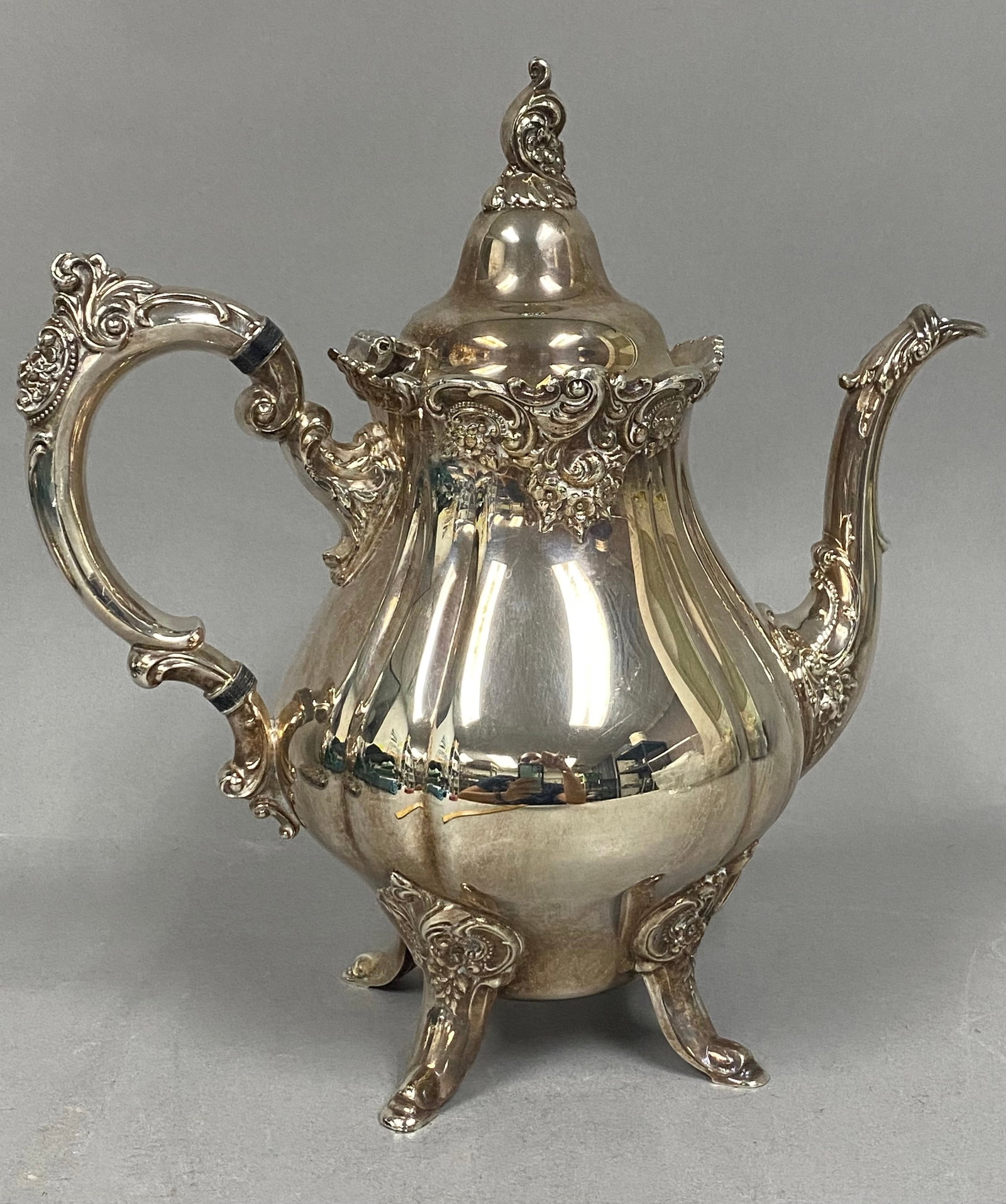 Wallace Baroque Silverplate Coffee Pot: This silver-plated coffee pot is produced in the Baroque pattern by Wallace Silversmiths, identified by model number 281. The ornate bulbous body features deep floral and shell relief, resting on