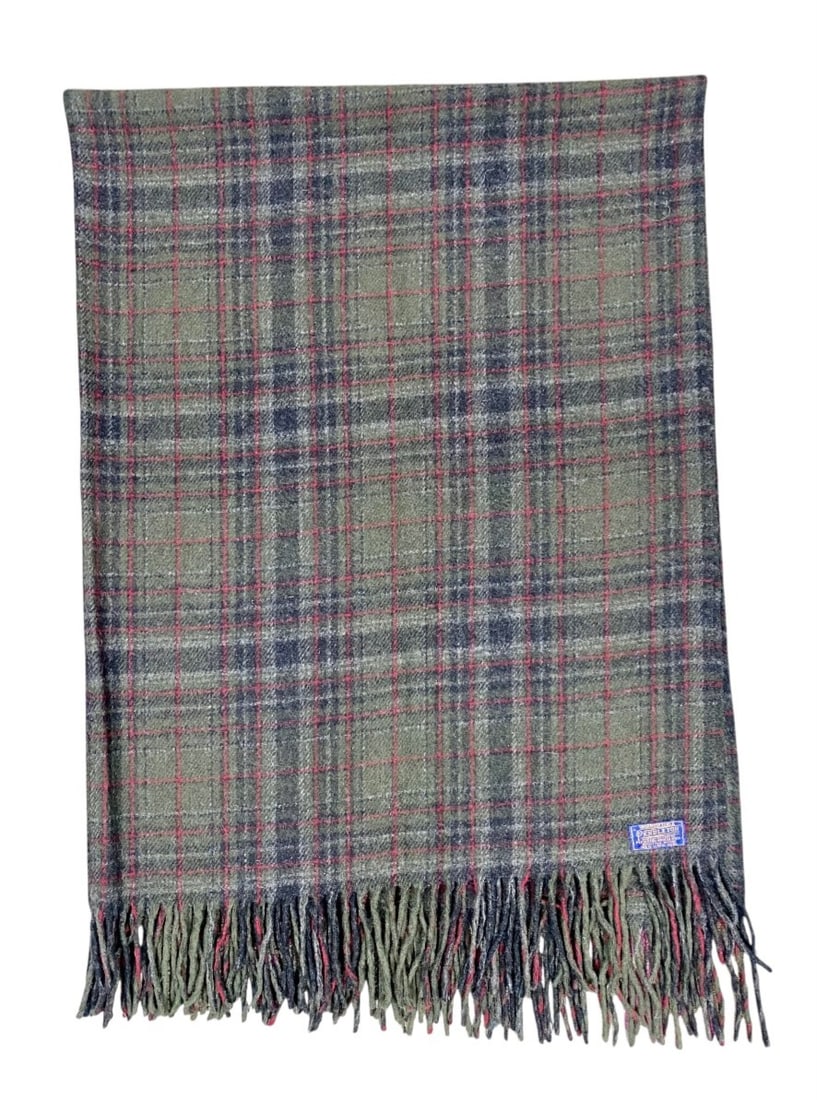 Pendleton Plaid Virgin Wool Throw: This Pendleton throw blanket is constructed from 100% virgin wool and features a classic plaid pattern in olive green, charcoal grey, and red accent stripes. The textile is finished with self-fringed