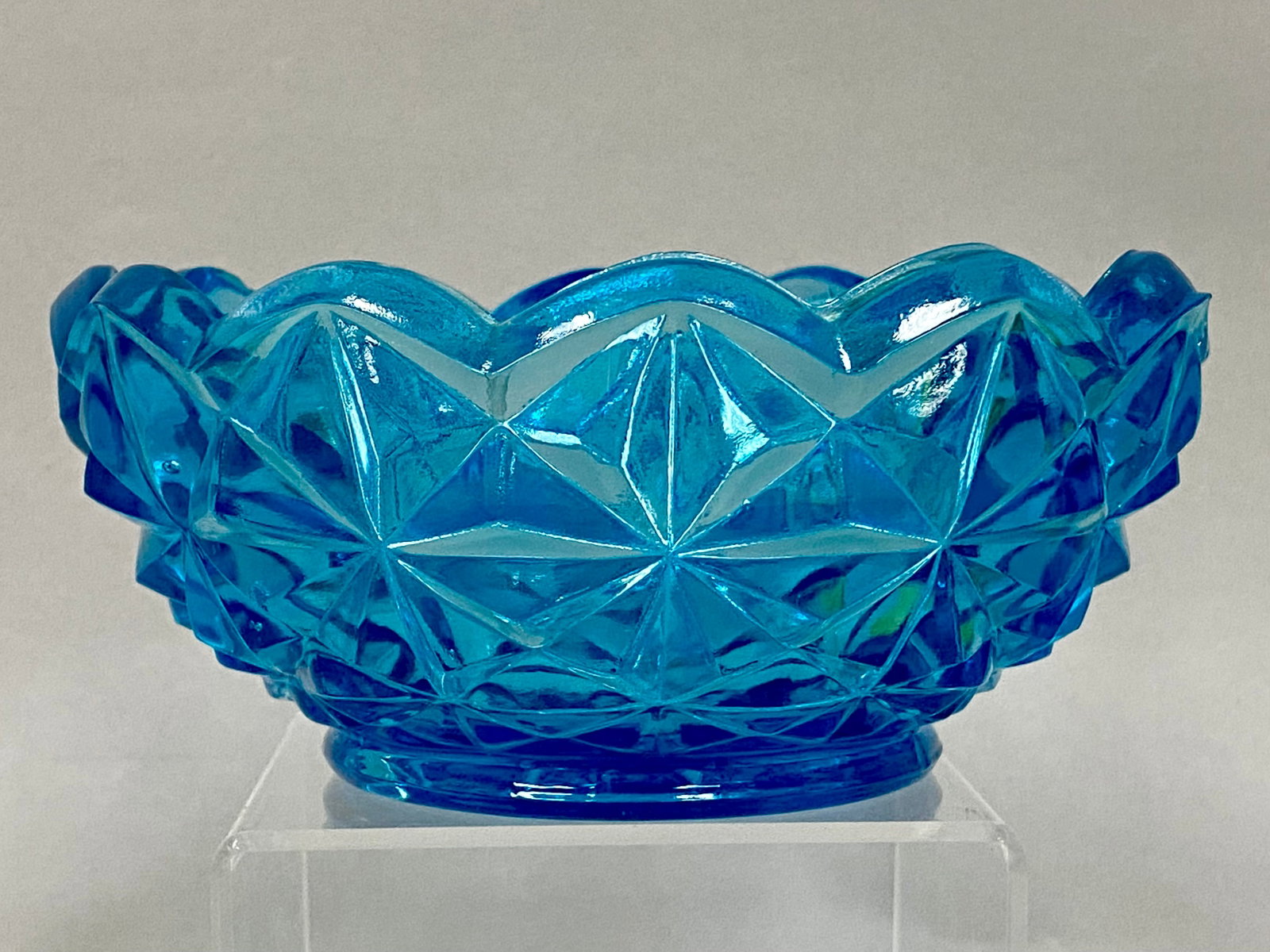 Indiana Glass Monticello Aqua Bowl: This Indiana Glass nut or candy bowl in the Monticello pattern is crafted from aqua blue pressed glass. The body features a geometric diamond point design with a scalloped rim and a starburst radial
