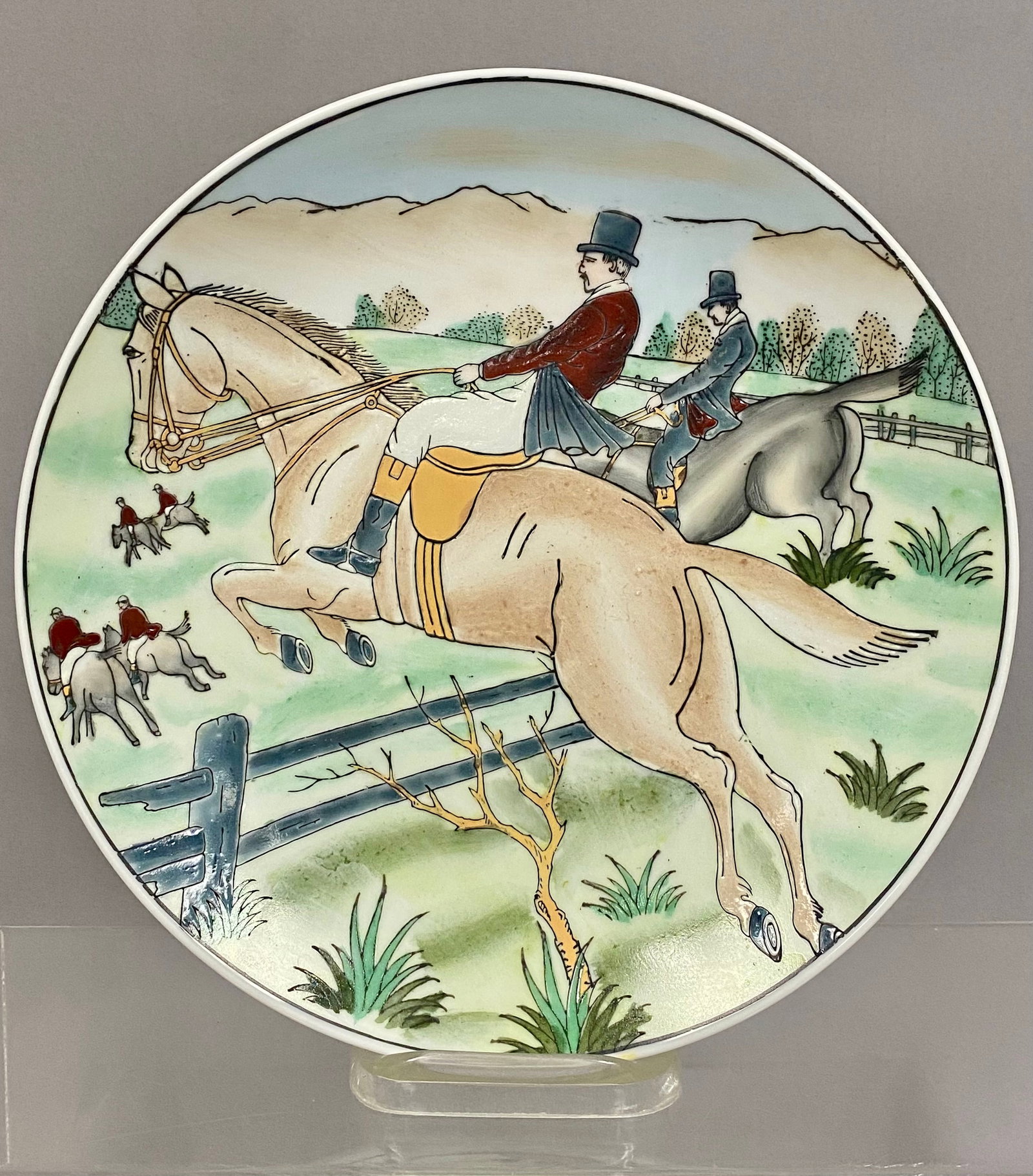 Fox Hunt Decorative Porcelain Plate: This porcelain plate features an equestrian scene depicting a traditional fox hunt. The decoration is executed with raised enamel outlines showing riders in formal attire jumping a fence within a