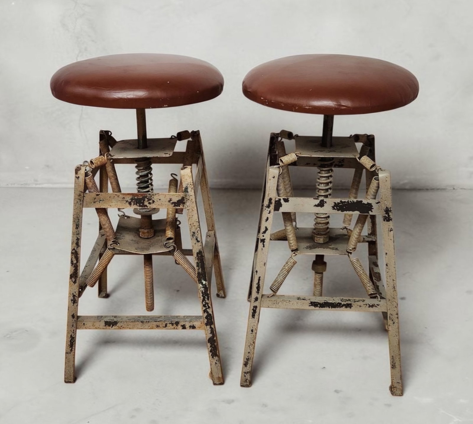 Pair Hamilton Spring Stools: AHeavily distressed overall. The metal frames and springs exhibit widespread surface oxidation, pitting, and significant paint loss. A couple of the springs are missing. The vinyl upholstery shows vis