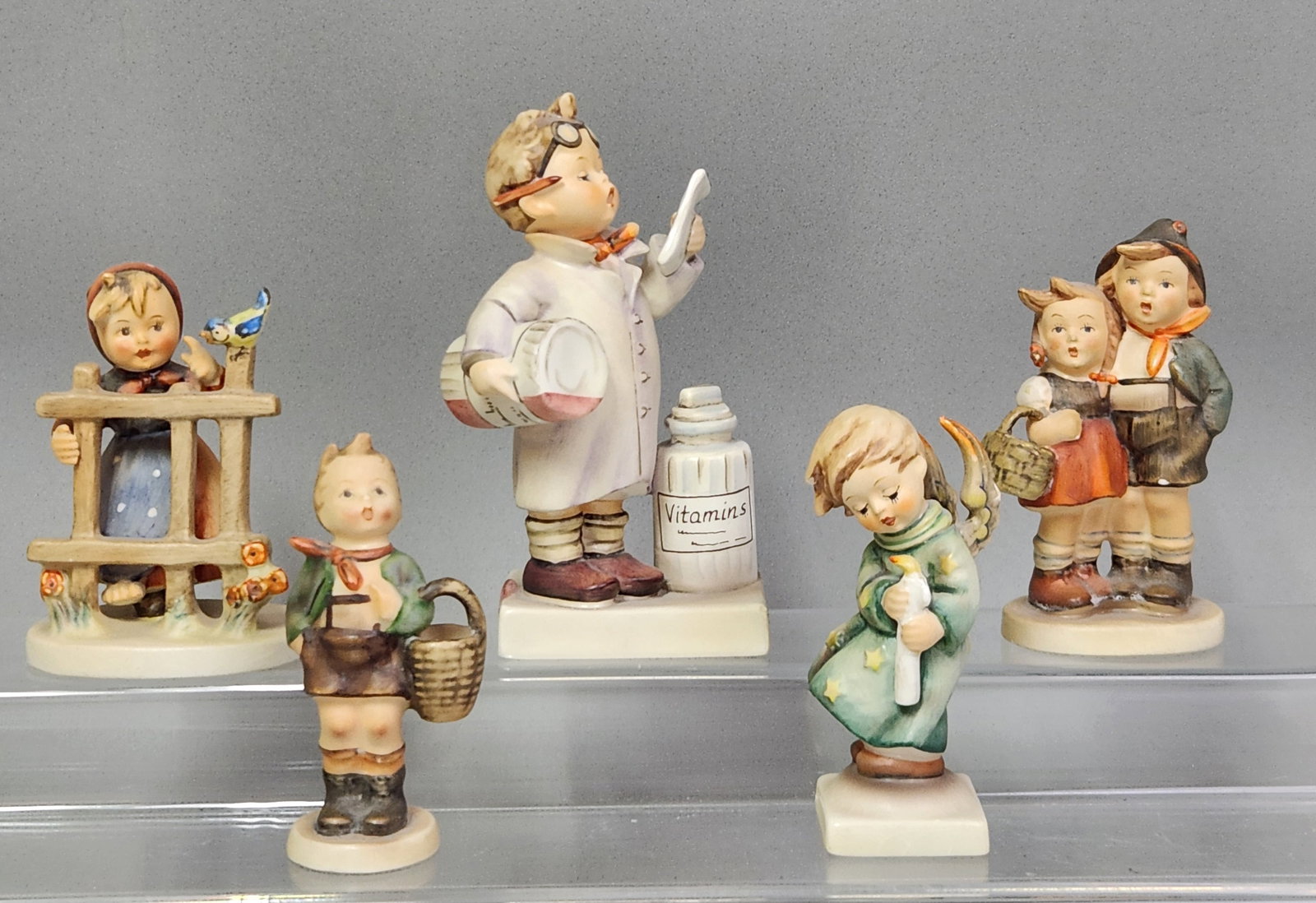 Goebel Hummel Figurines: The assortment includes well-known models such as the Little Pharmacist, Apple Tree Girl, Merry Wanderer, Heavenly Angel, and Farewell. See pictures for measurements. Generally good condition with vis