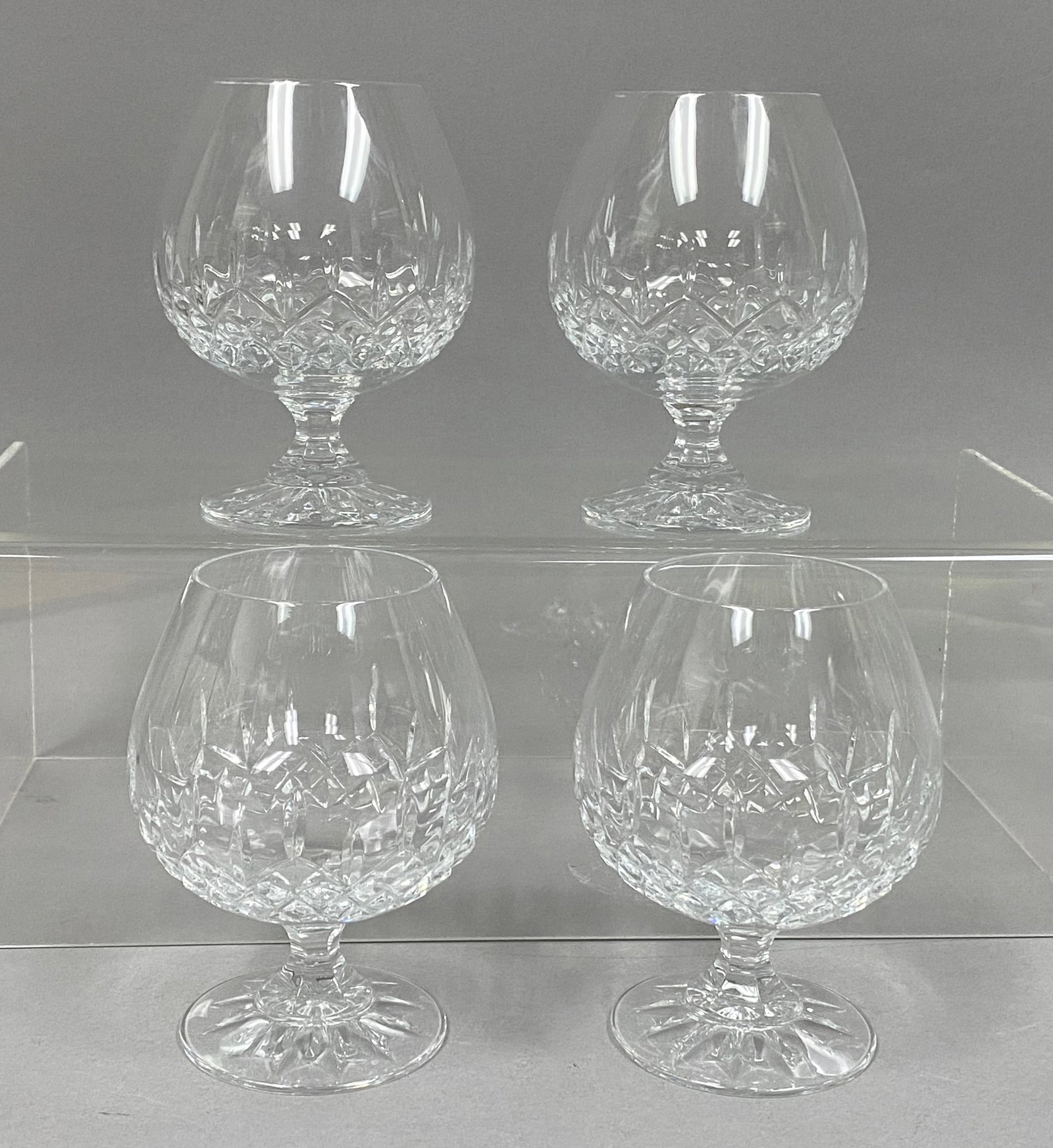 Four Galway Crystal Brandy Snifters: A set of four clear lead crystal brandy snifters manufactured by Galway Crystal, featuring a traditional deep-cut diamond pattern across the lower bowl. Each vessel is supported by a faceted stem and