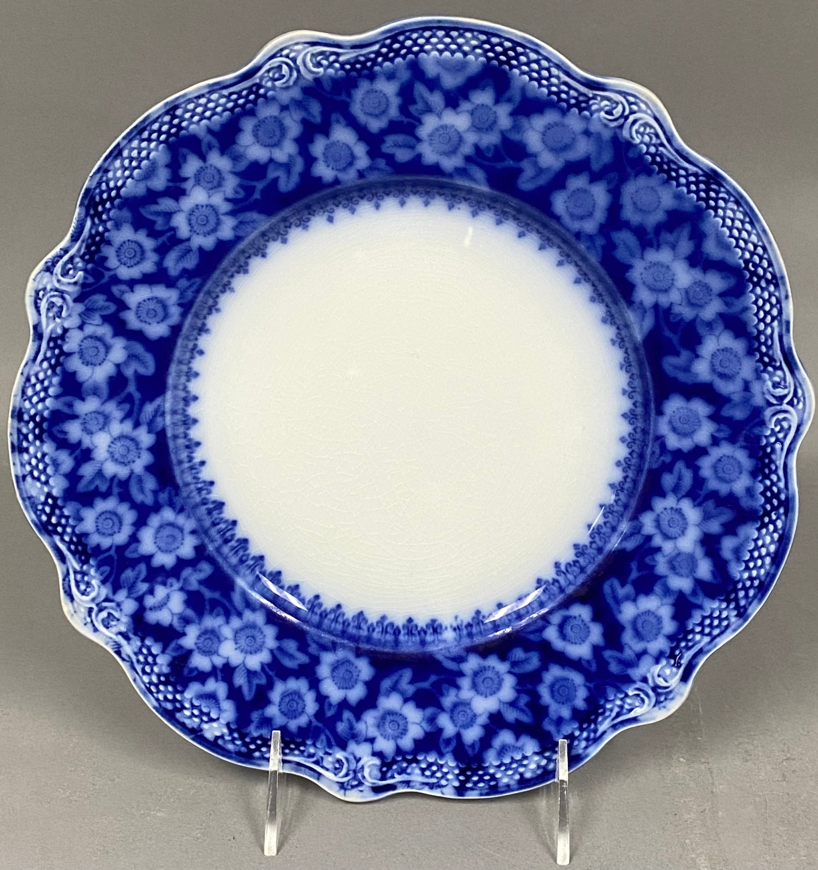 Grindley Grace Flow Blue Ironstone Plate: A late 19th-century ironstone plate in the Grace pattern by W.H. Grindley and Co. The piece features a dense cobalt blue floral border with a lattice-work rim and a scalloped edge. The underside