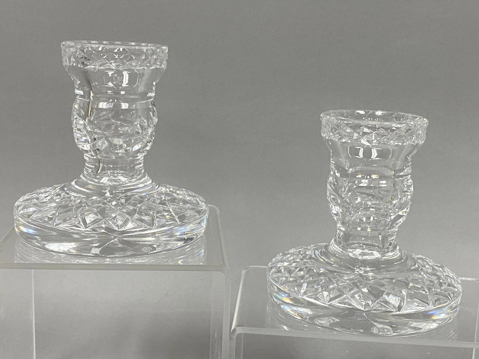 A Pair of Waterford Glandore Candlesticks: A matched pair of lead crystal candlestick holders in the Glandore pattern by Waterford. Each piece features a flared, diamond-cut rim above a faceted baluster stem and a wide circular base decorated 