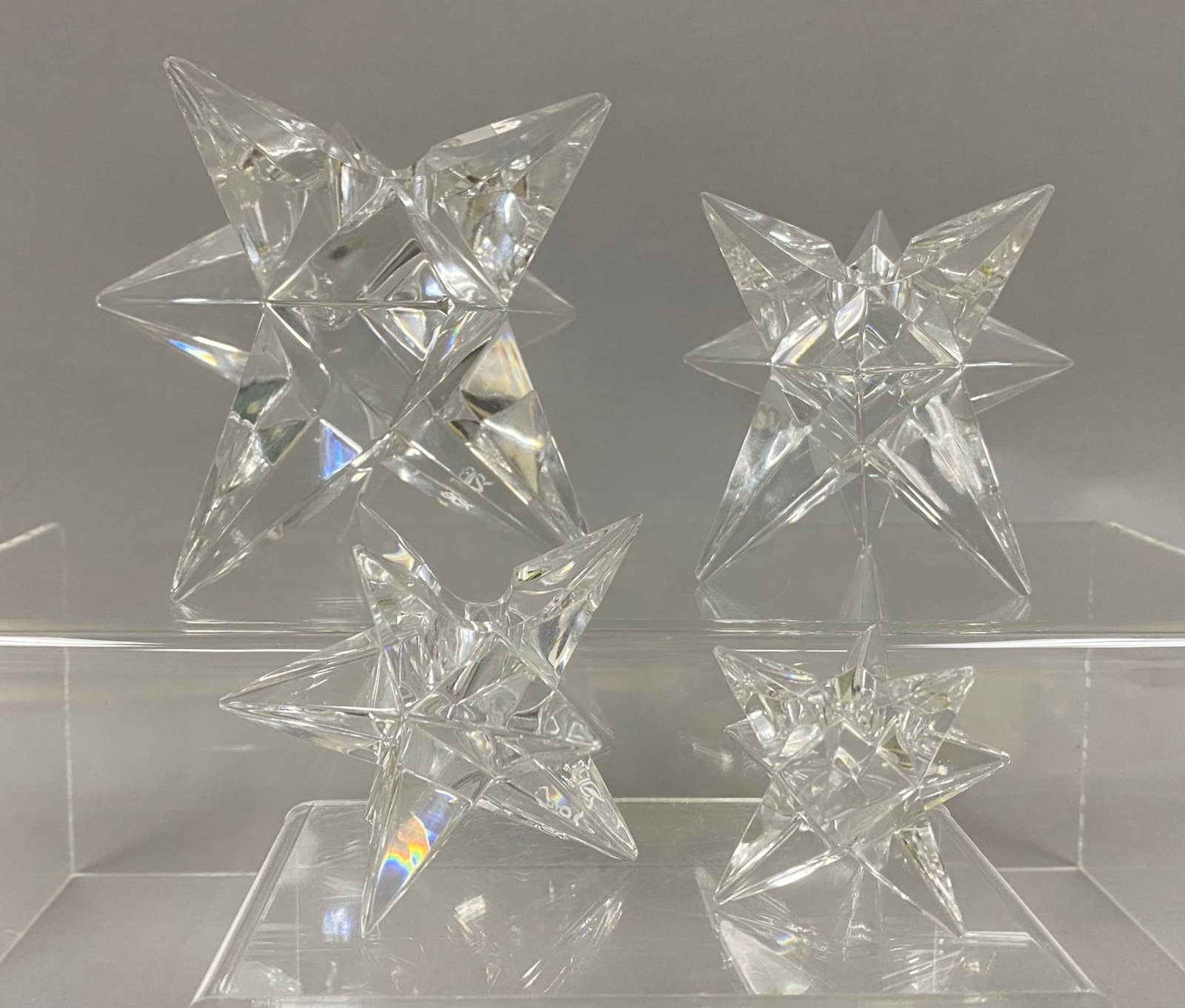 Set of 4 Rosenthal Star Candle Holders: A set of four graduated clear lead crystal candle holders by Rosenthal. Each piece is modeled as a multi-pointed star with a central cylindrical recess and bears an acid-etched manufacturer mark on on