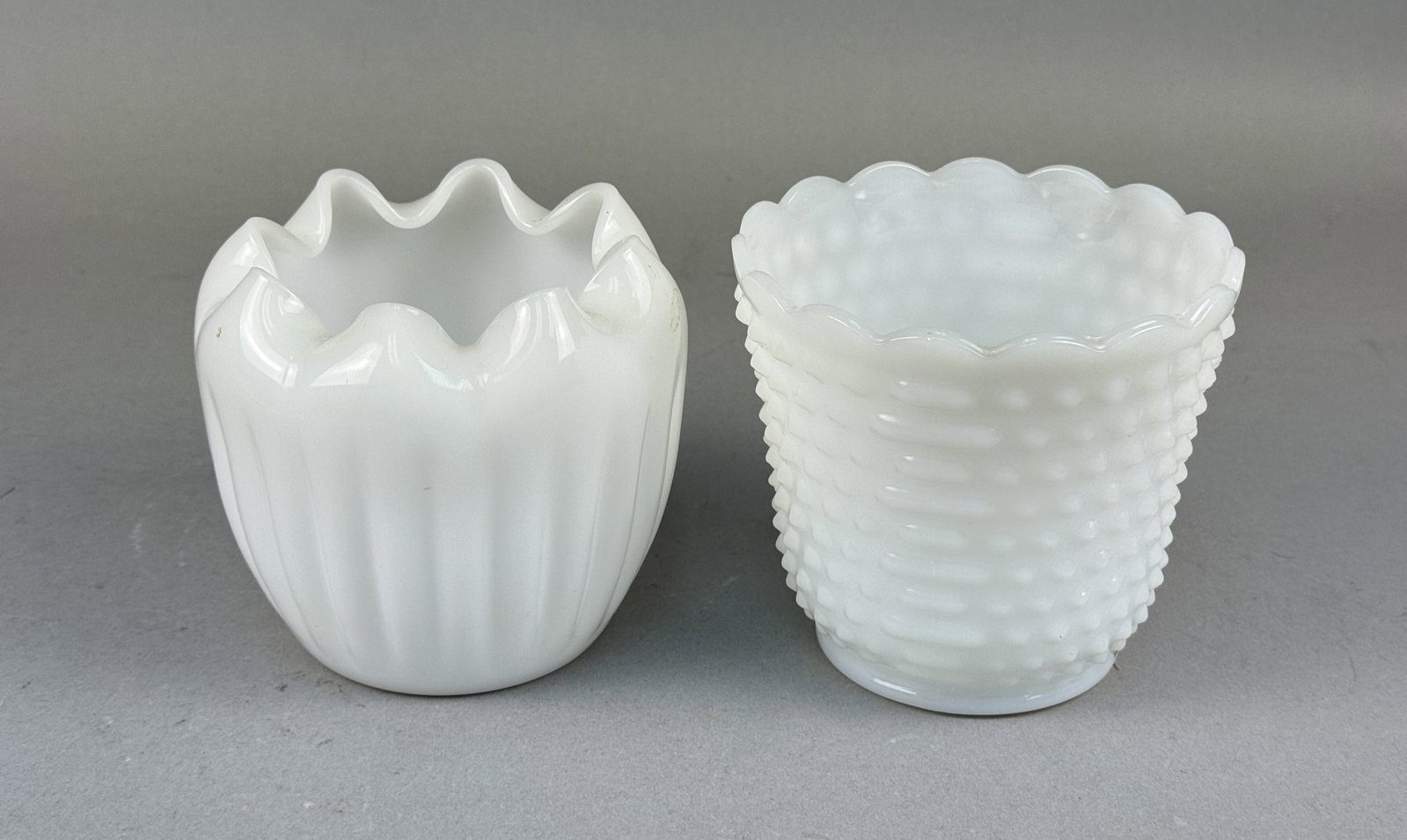 Fire-King and Hobnail Milk Glass Planters: This lot comprises a Fire-King fluted milk glass planter and a milk glass hobnail pattern planter. The Fire-King piece features vertical ribbing and a ruffled rim, bearing a clear maker's mark on the 
