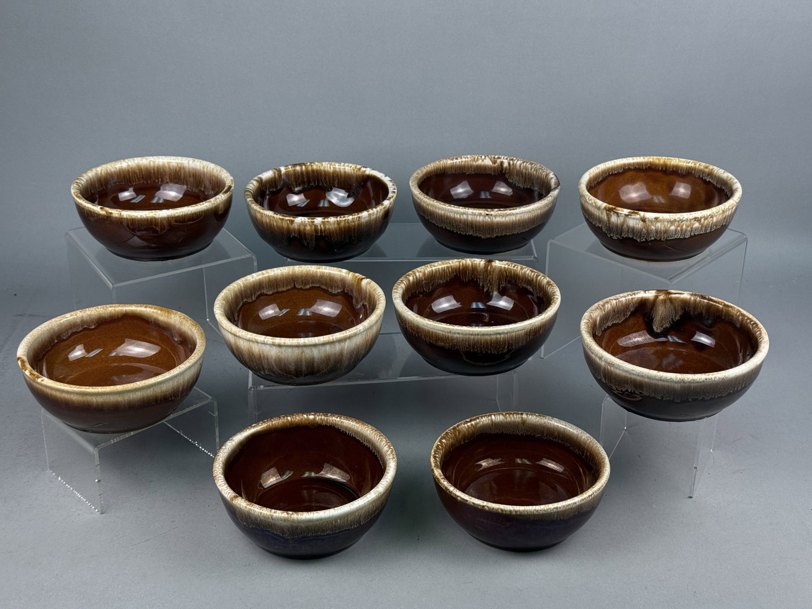 Set of Ten Nelson McCoy Brown Drip Bowls: A set of ten glazed earthenware bowls by Nelson McCoy featuring a classic brown drip glaze. Eight examples bear the Kathy Kale USA circular backstamp with a stylized K, while remaining pieces are