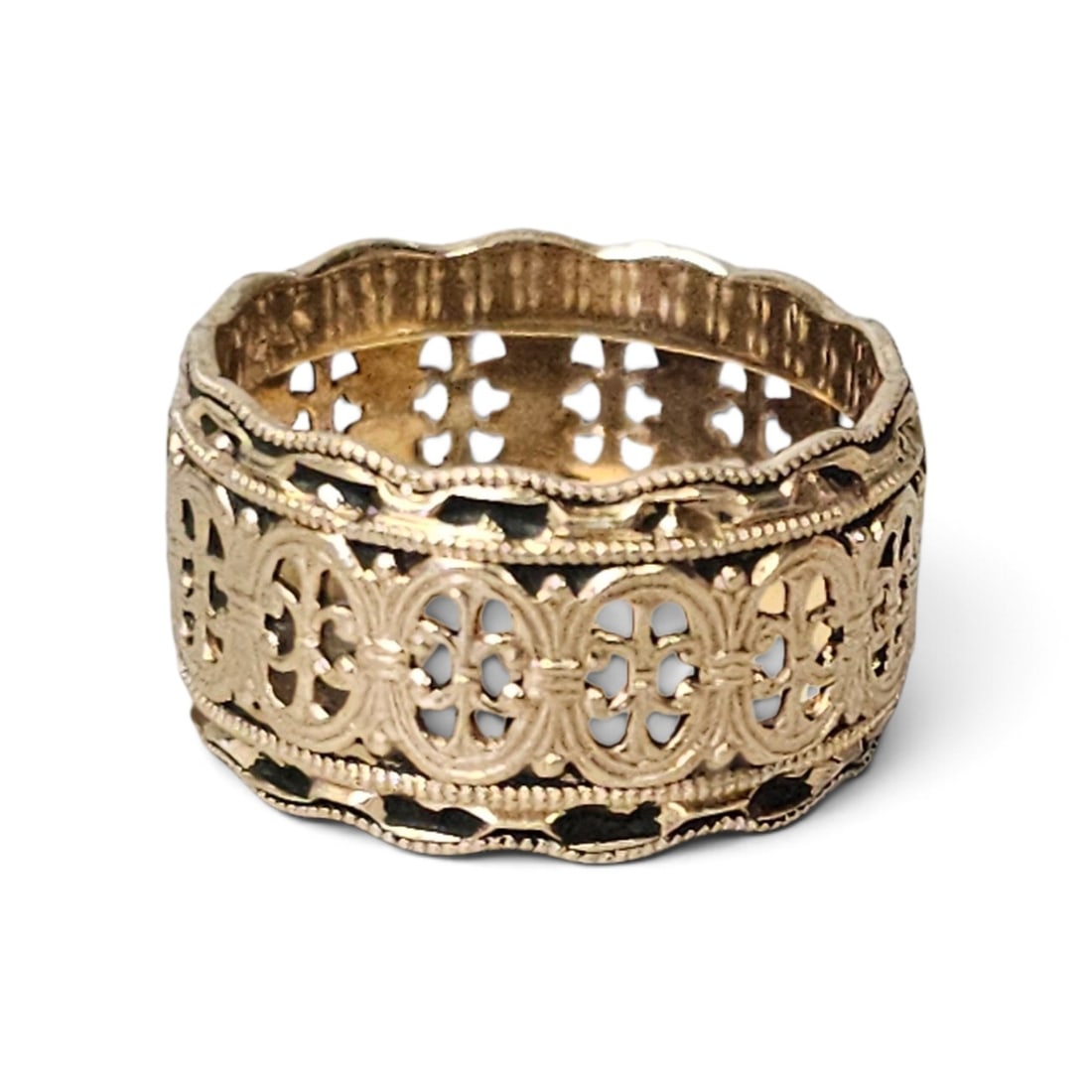 14K Gold Filigree Band Ring 7.6 Grams: This wide 14 karat yellow gold band features a continuous pierced openwork design of stylized foliate and scroll motifs. The ring is bordered by scalloped edges with milgrain detailing and shows inten