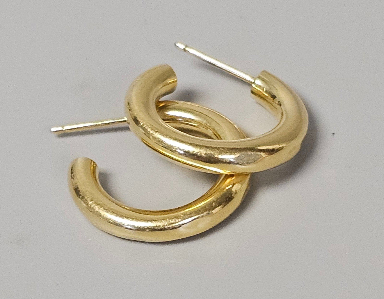 14K Yellow Gold Hoop Earrings 2.1 Grams: This pair of contemporary C-hoop earrings features a chunky profile with a textured, organic surface. Each hoop measures 0.5 inches in diameter and the pair has a combined weight of 2.1 grams. These e