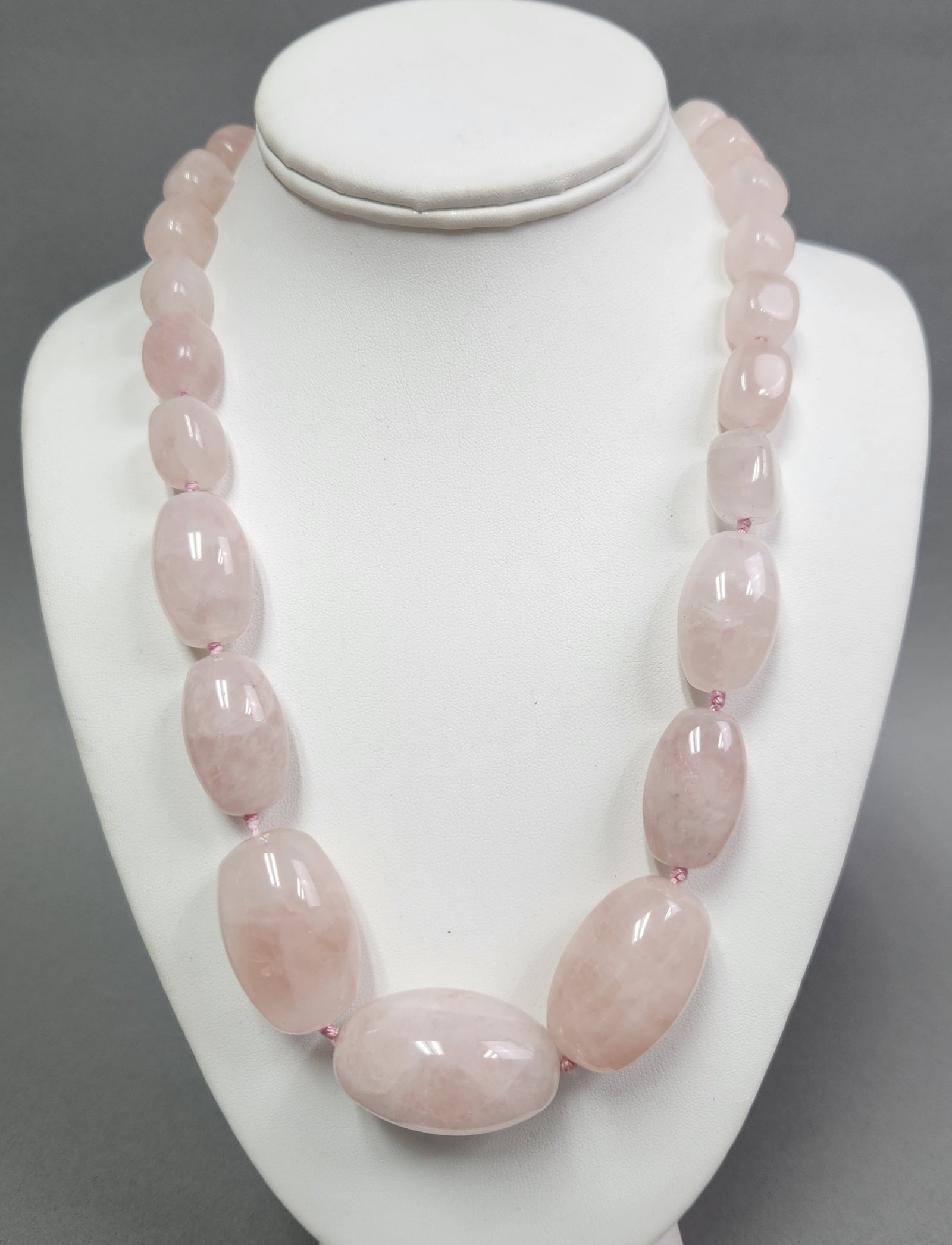 Rose Quartz Bead Necklace: A graduated bead necklace featuring polished, light pink rose quartz stones hand-knotted on pink silk thread. The piece is finished with a sterling silver lobster claw clasp marked 925. It measures 31