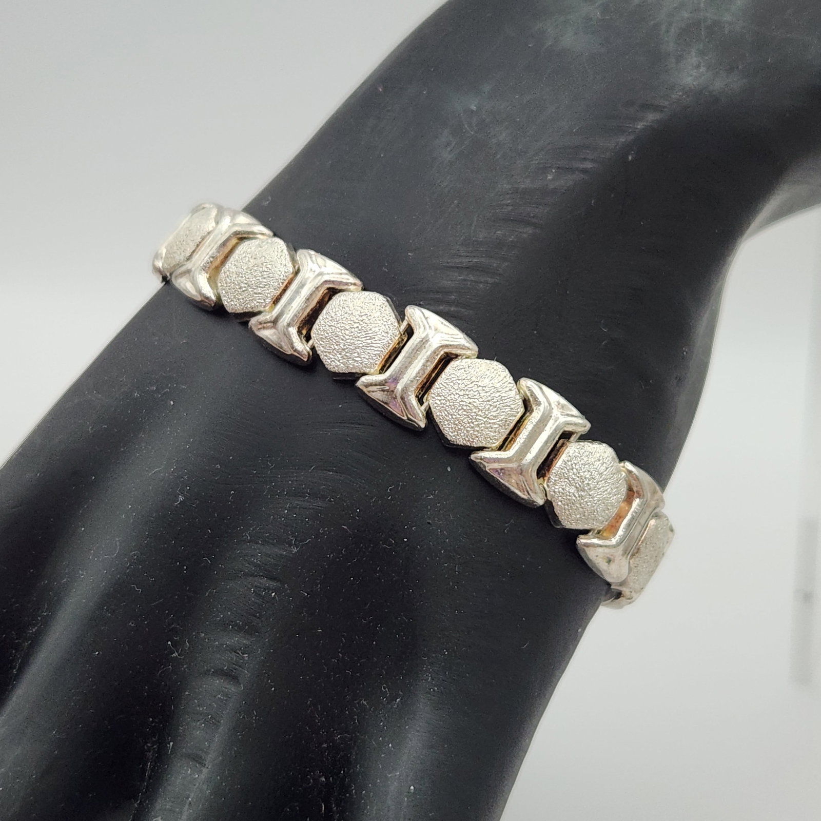 Sterling Geometric Link Bracelet 11.3 Grams: This sterling silver articulated link bracelet features a repeating motif of polished hourglass-shaped links alternating with textured hexagonal nugget-style links. Length: Approximately 7.25 inches W