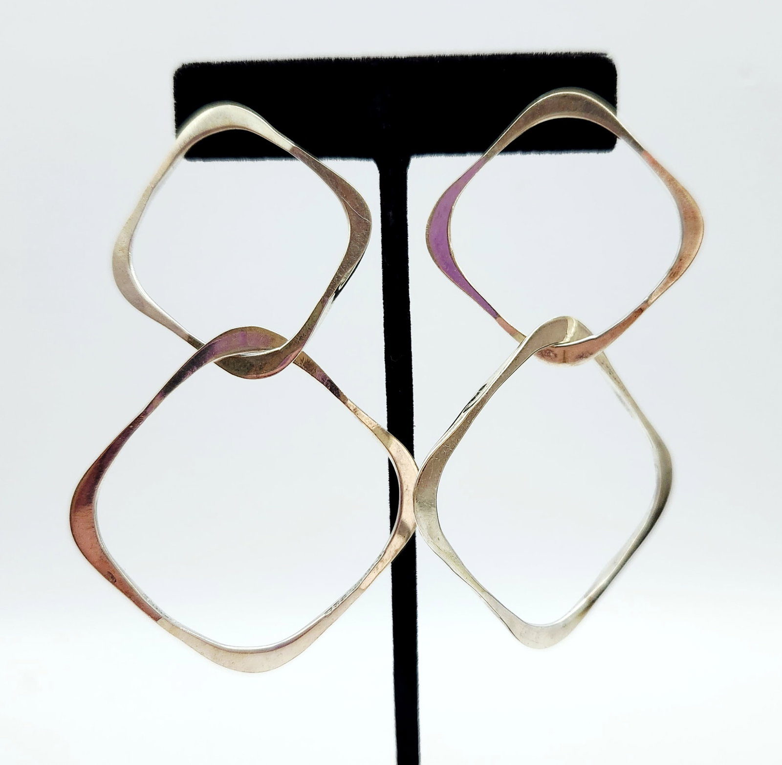 Sterling Modernist Earrings: A matched pair of sterling silver drop earrings featuring a modernist geometric design with two interlocking, irregularly shaped squarish hoops. Length: 3.5 inches Width: 2 inches Weight: 14.7 grams. 