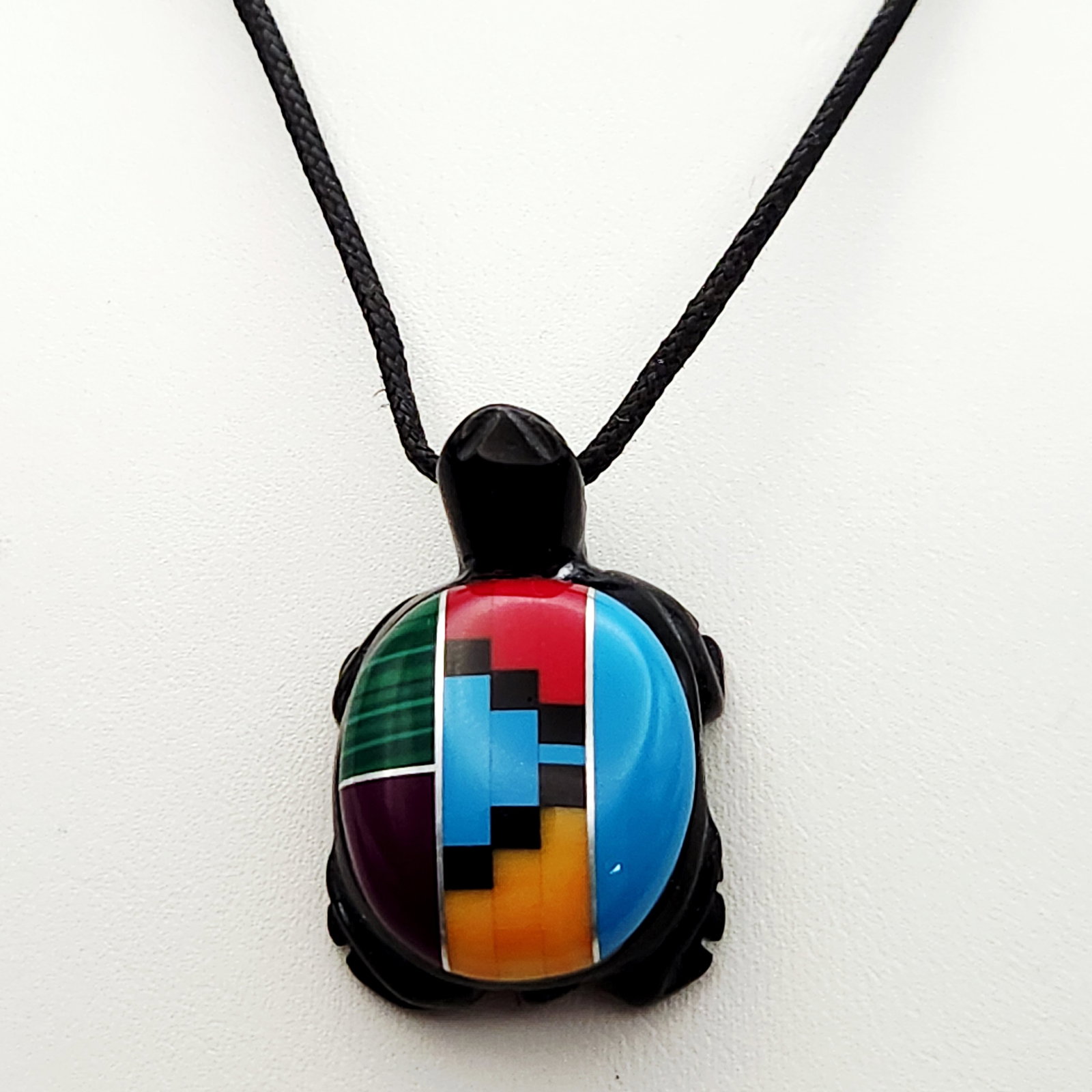 Southwest Zuni Inlaid Turtle Necklace: This necklace features a carved black stone turtle fetish pendant detailed with a multi-stone mosaic channel inlay shell. The inlay consists of malachite, turquoise, and various colored shells and sto