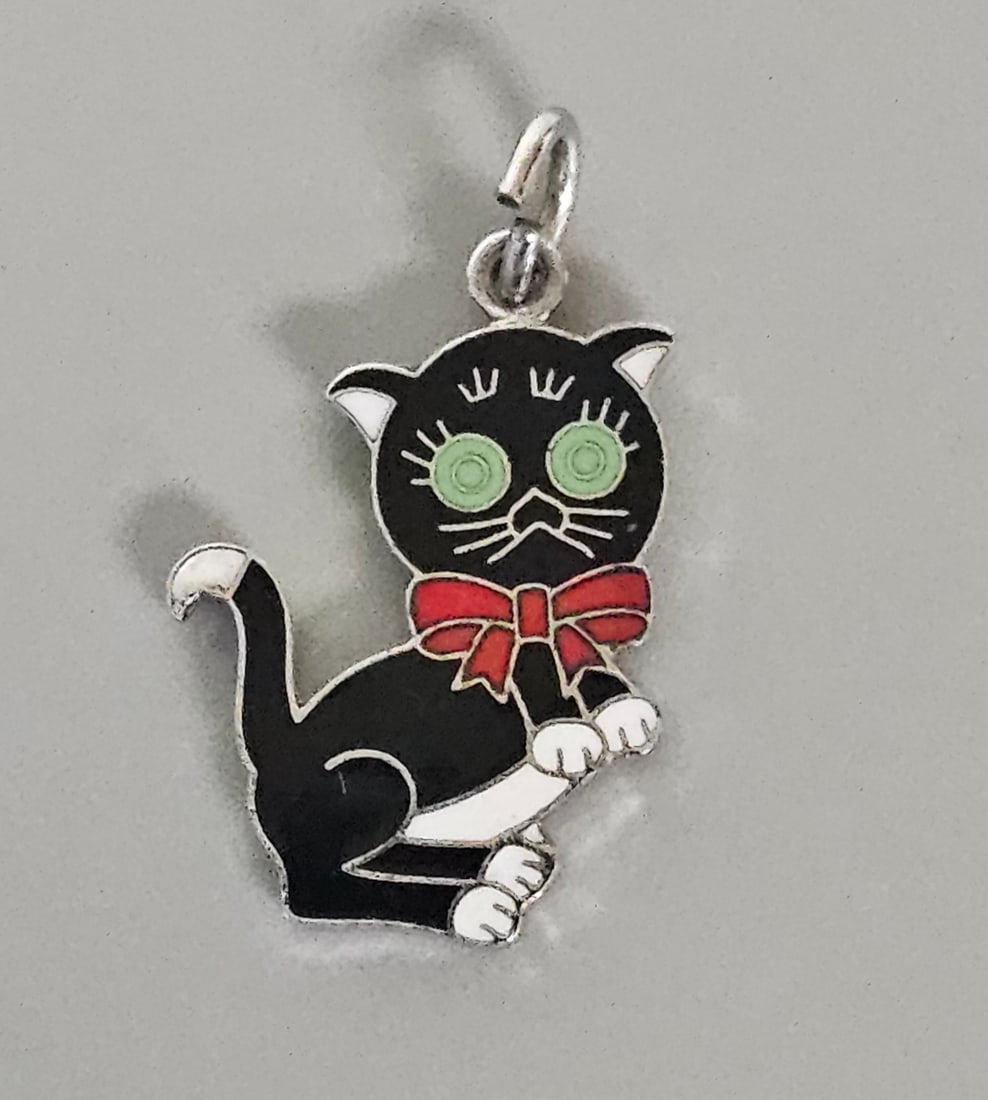 Vintage Sterling Enamel Cat Charm 2.0 Grams: This mid-century style charm is crafted from sterling silver with multi-colored enamel depicting a stylized black cat with a red bow and green eyes. The reverse is stamped STERLING and exhibits a text