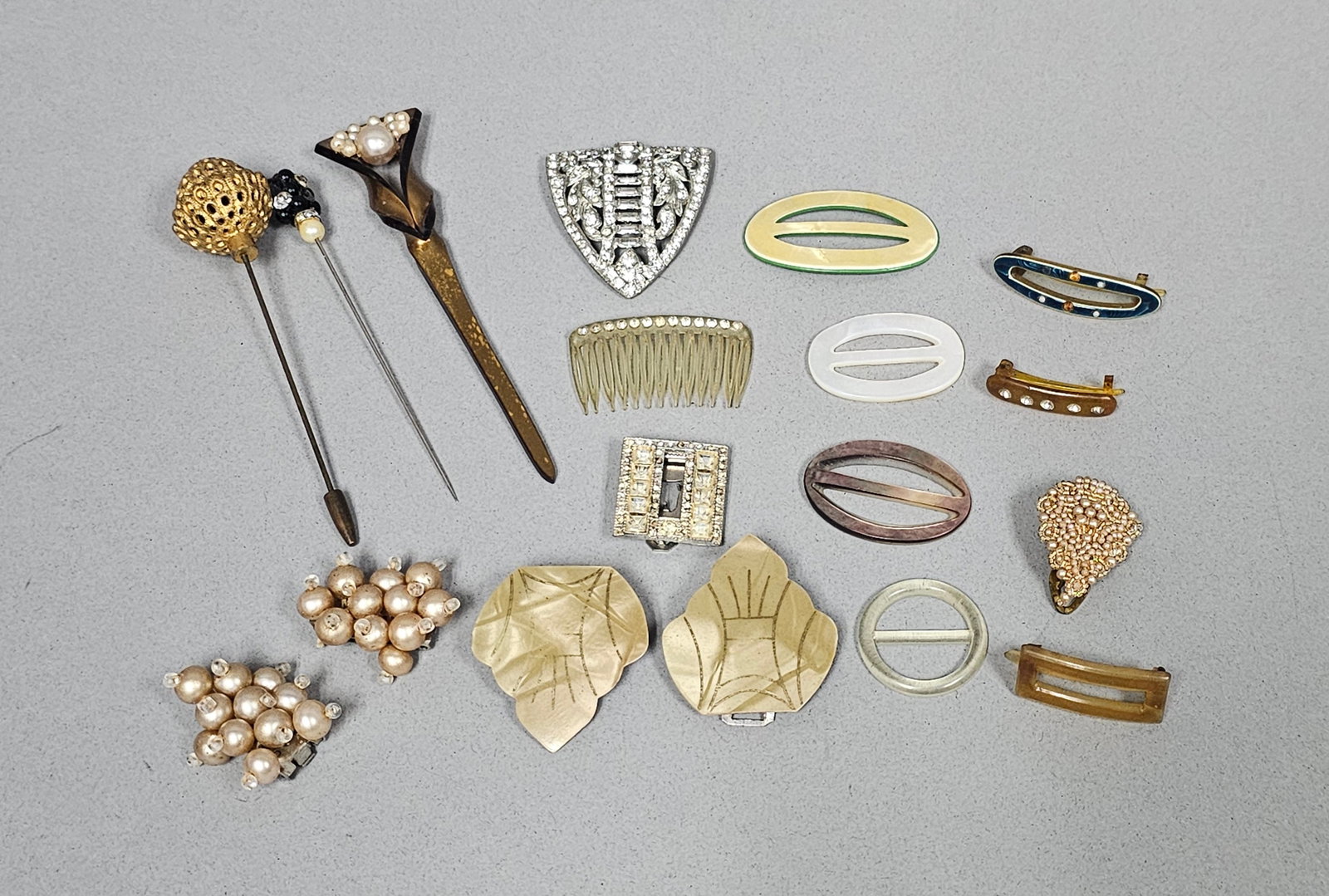 Vintage Costume Jewelry Collection: Collection of vintage costume jewelry and hair accessories, featuring Art Deco and Mid-Century Modern designs. The lot includes hat pins, rhinestone dress clips, celluloid hair slides, and faux pearl