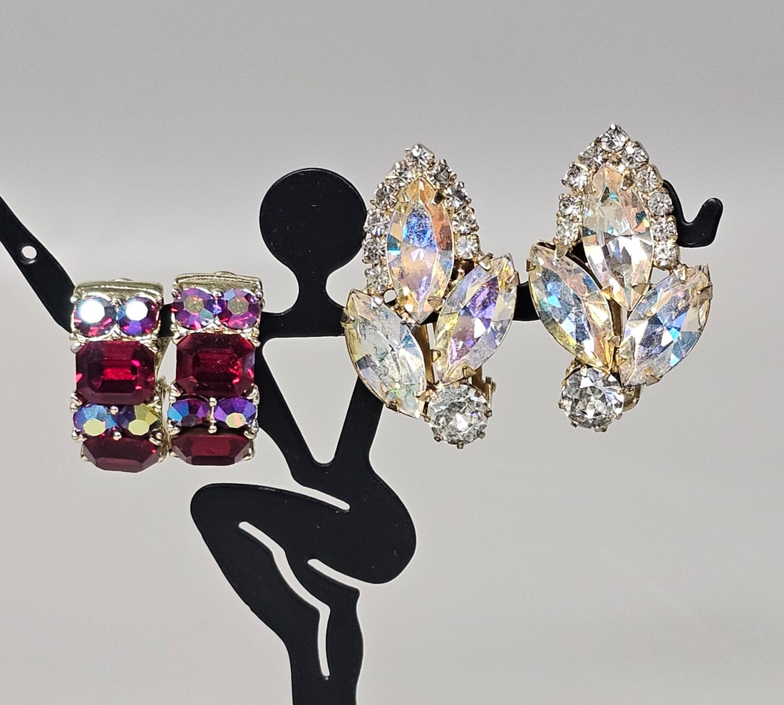 Lisner and Weiss Rhinestone Earrings: This lot comprises two pairs of mid-century clip-on earrings from prominent American makers. The Lisner J-hoop earrings are crafted in silver-tone metal and set with emerald-cut red glass stones and