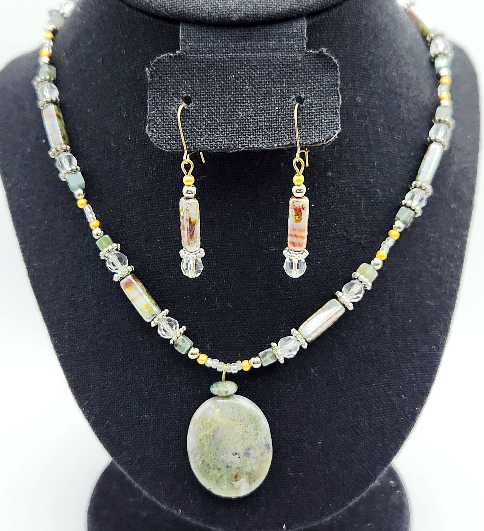 Stone Pendant Necklace & Earrings: This jewelry suite includes a single-strand necklace and matching drop earrings featuring mottled green and gray stone accents, measuring approximately 19 inches long with a 1.5-inch pendant. Good