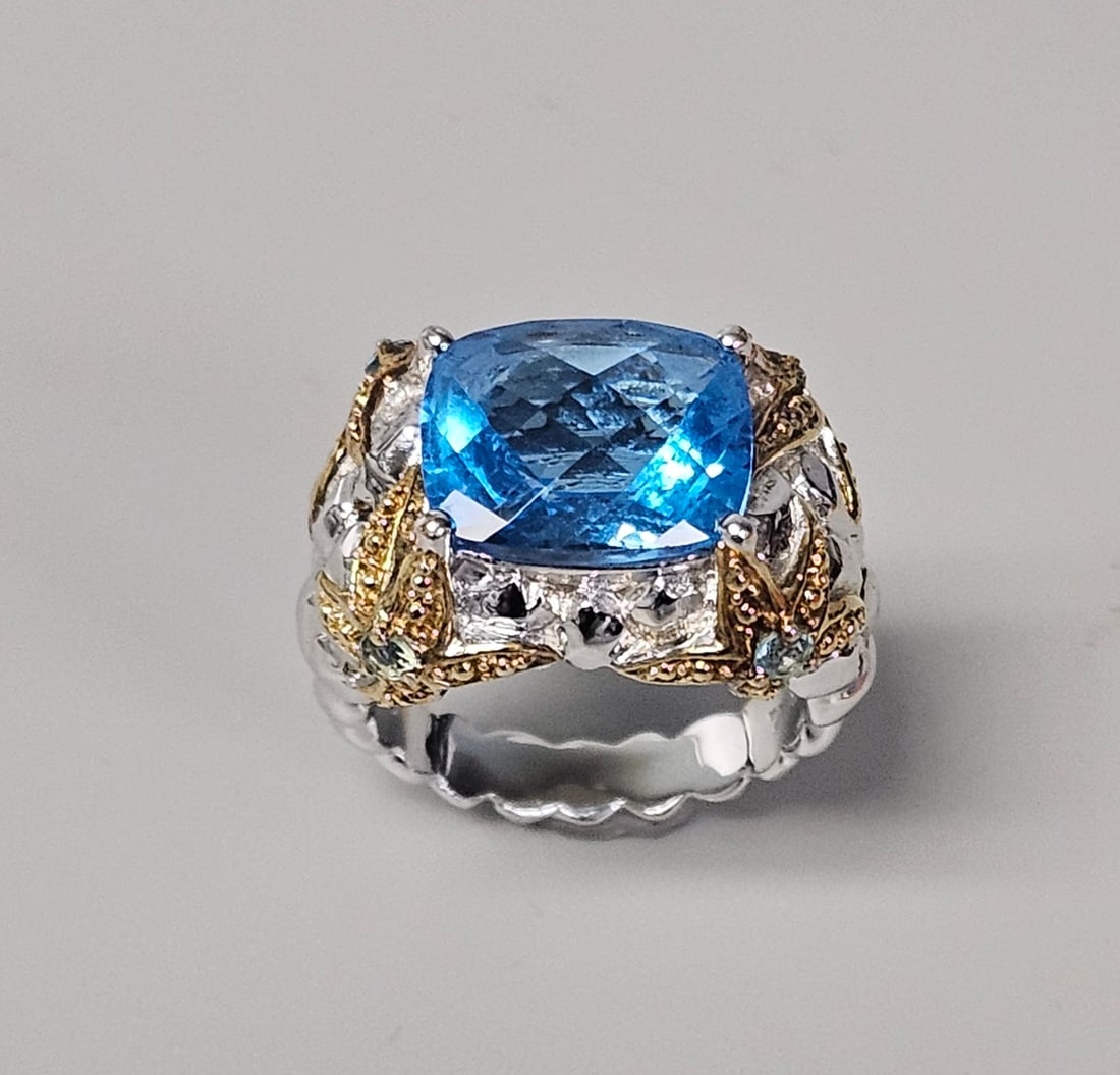 Sterling Silver Nautical Starfish Cocktail Ring: A nautical-themed cocktail ring crafted in sterling silver with yellow gold-toned accents. The center is set with a large rectangular cushion-cut blue stone, flanked by four starfish motifs featuring
