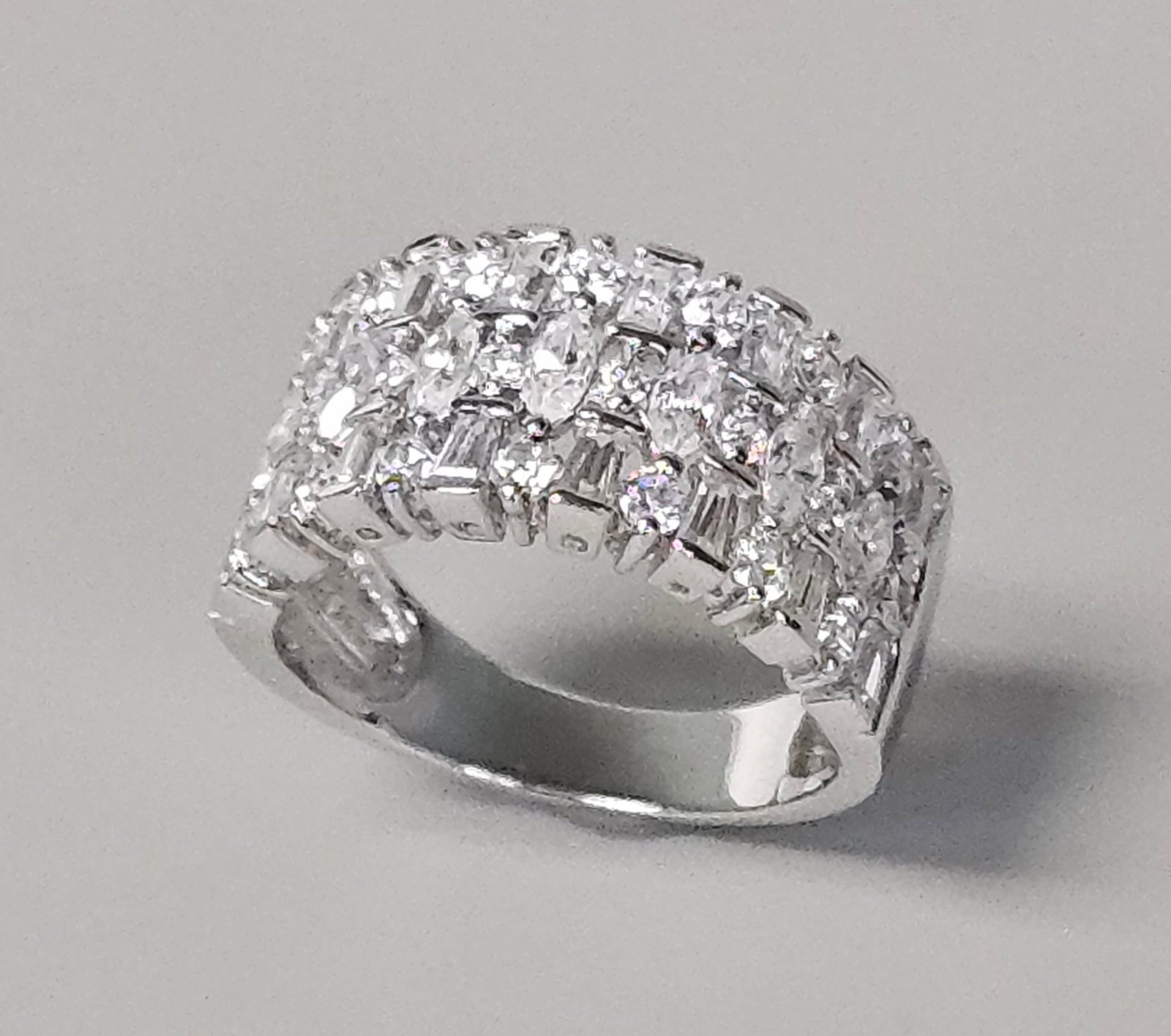 Sterling Silver Cubic Zirconia Cocktail Ring: This sterling silver cocktail ring features a wide band set with multiple rows of clear cubic zirconia. The central row is composed of vertically set marquise-cut stones, flanked by tiered rows of