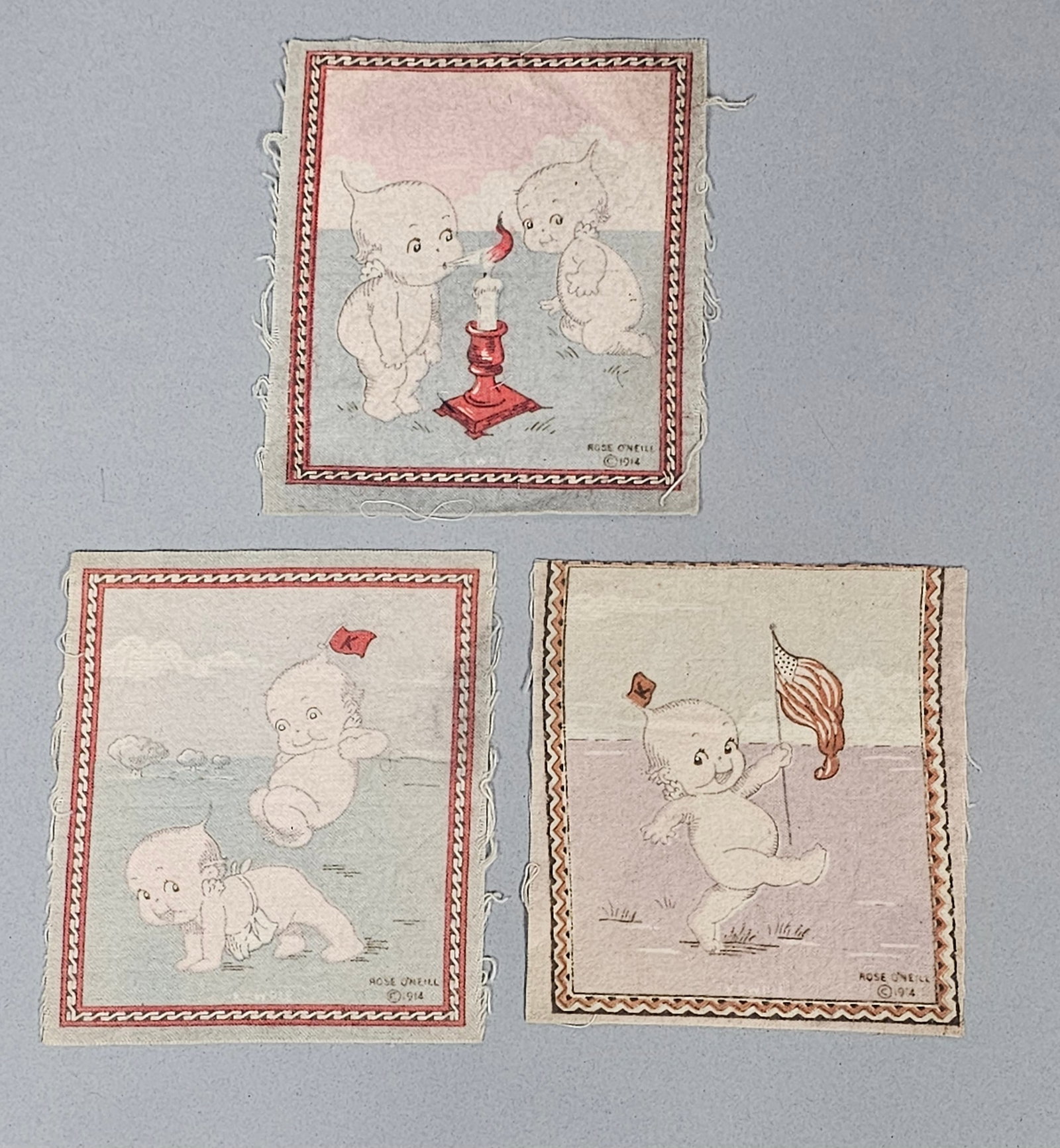 Trio of 1914 Rose O'Neill Kewpie Tobacco Flannels: A trio of woven cotton flannel panels featuring the Kewpie characters created by Rose O'Neill. Each piece is decorated with a specific scene, including patriotic imagery and domestic vignettes, framed