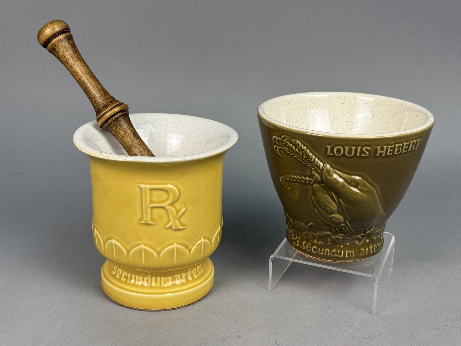 McCoy and Eli Lilly Pharmaceutical Mortars: This lot features a McCoy Pottery yellow glazed mortar commemorating the 150th anniversary of the United States Pharmacopeia and an Eli Lilly olive green mortar honoring Louis Hebert. Both ceramic ves