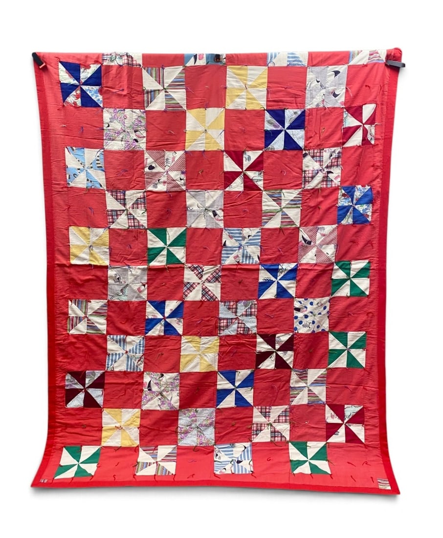 Vintage Mid-Century Pinwheel Utility Quilt: This hand-pieced cotton utility quilt features a checkerboard layout of solid red squares alternating with pieced pinwheel blocks. The pinwheels incorporate a variety of mid-century printed and solid