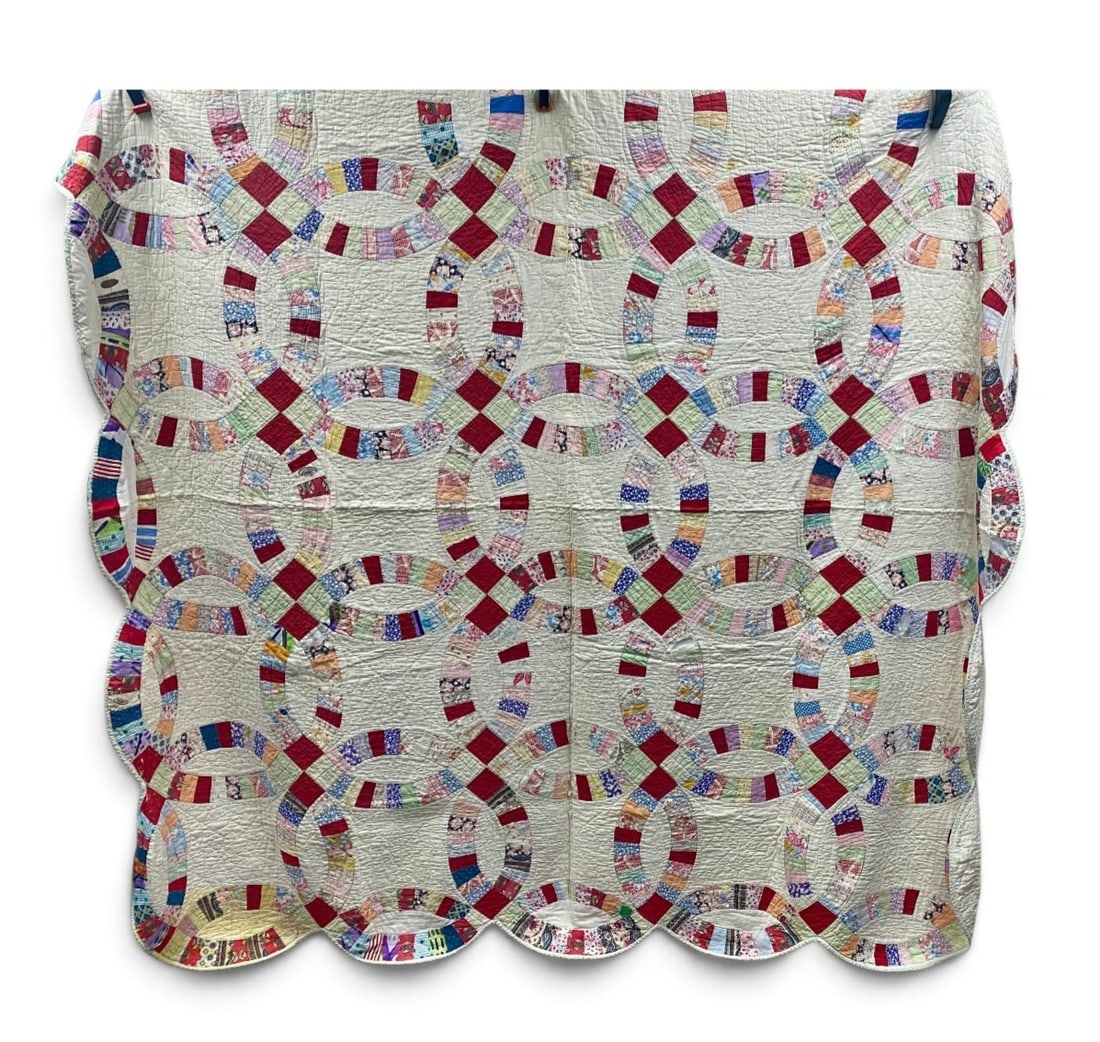 Double Wedding Ring Cotton Quilt: This hand-pieced and hand-quilted cotton textile is rendered in a Double Wedding Ring pattern featuring multicolored scrap fabric rings against a white ground. The construction incorporates assorted