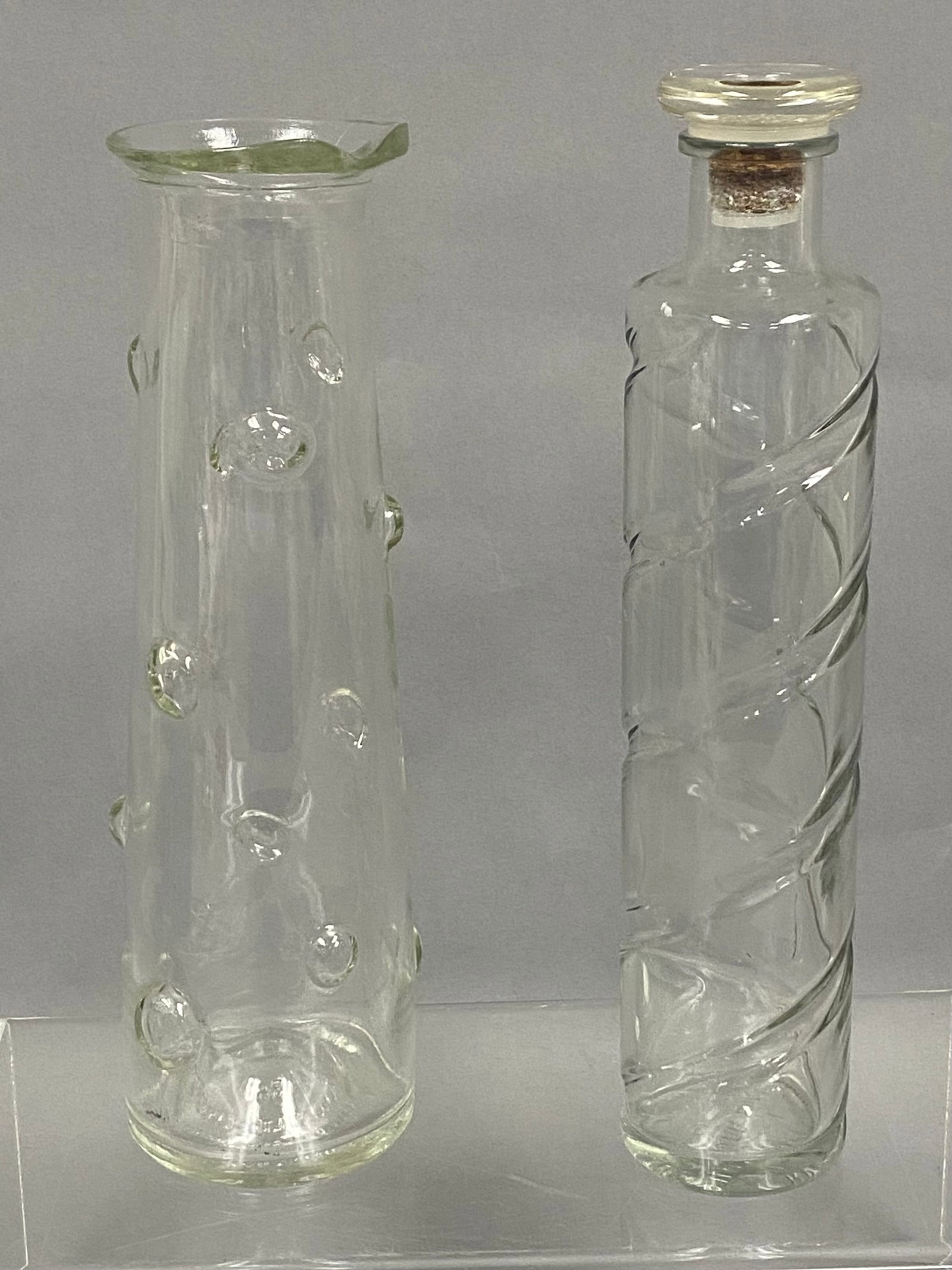 Two Vintage Glass Liquor Decanters: This lot features two mid-century clear glass bottles with unique textures and shapes. The Canadian Schenley bottle displays a tapered form with raised circular prunts and a flared, ruffled rim. The