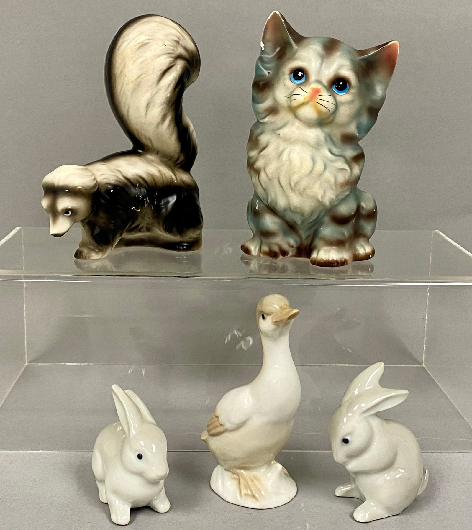 Five Japanese Ceramic Animal Figurines: This collection consists of five glazed ceramic figures including an Enesco skunk, an Otagiri goose, a pair of O-C M rabbits, and a cat planter. These hand-painted pieces were manufactured in Japan