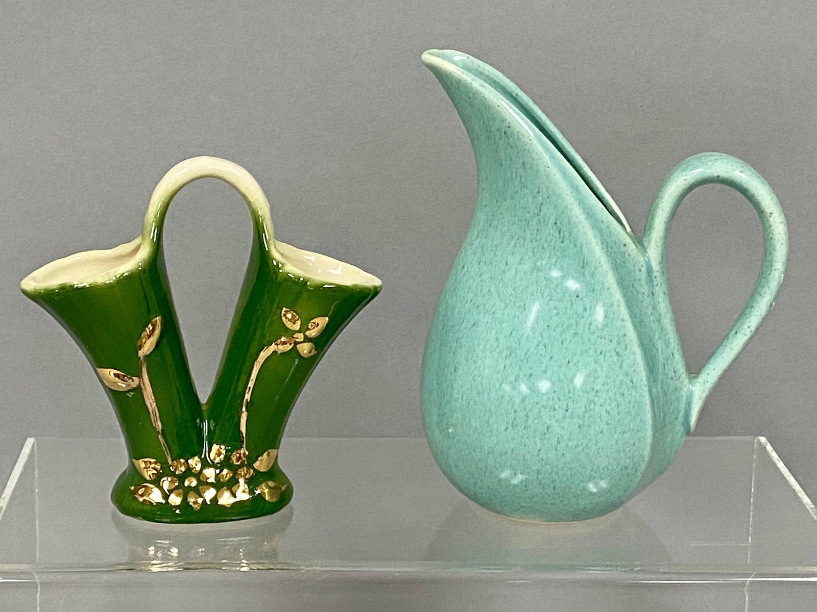 Two Vintage American Ceramic Pieces: This lot includes a Shafer twin-spouted earthenware vase and a mid-century modern speckled teal pitcher. The green-glazed Shafer vase features hand-applied floral motifs in 23 karat gold paste and is