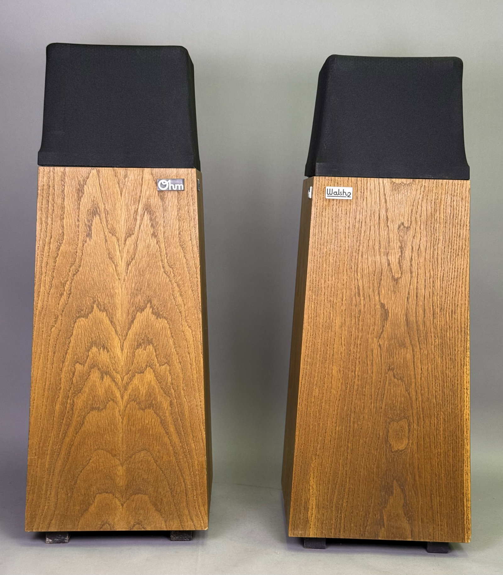 Pair of Ohm Walsh 2 Speakers: A pair of Ohm Acoustics Walsh 2 floor-standing loudspeakers featuring tapered oak veneer cabinets and black cloth top covers. These omnidirectional units incorporate unique driver assemblies protected