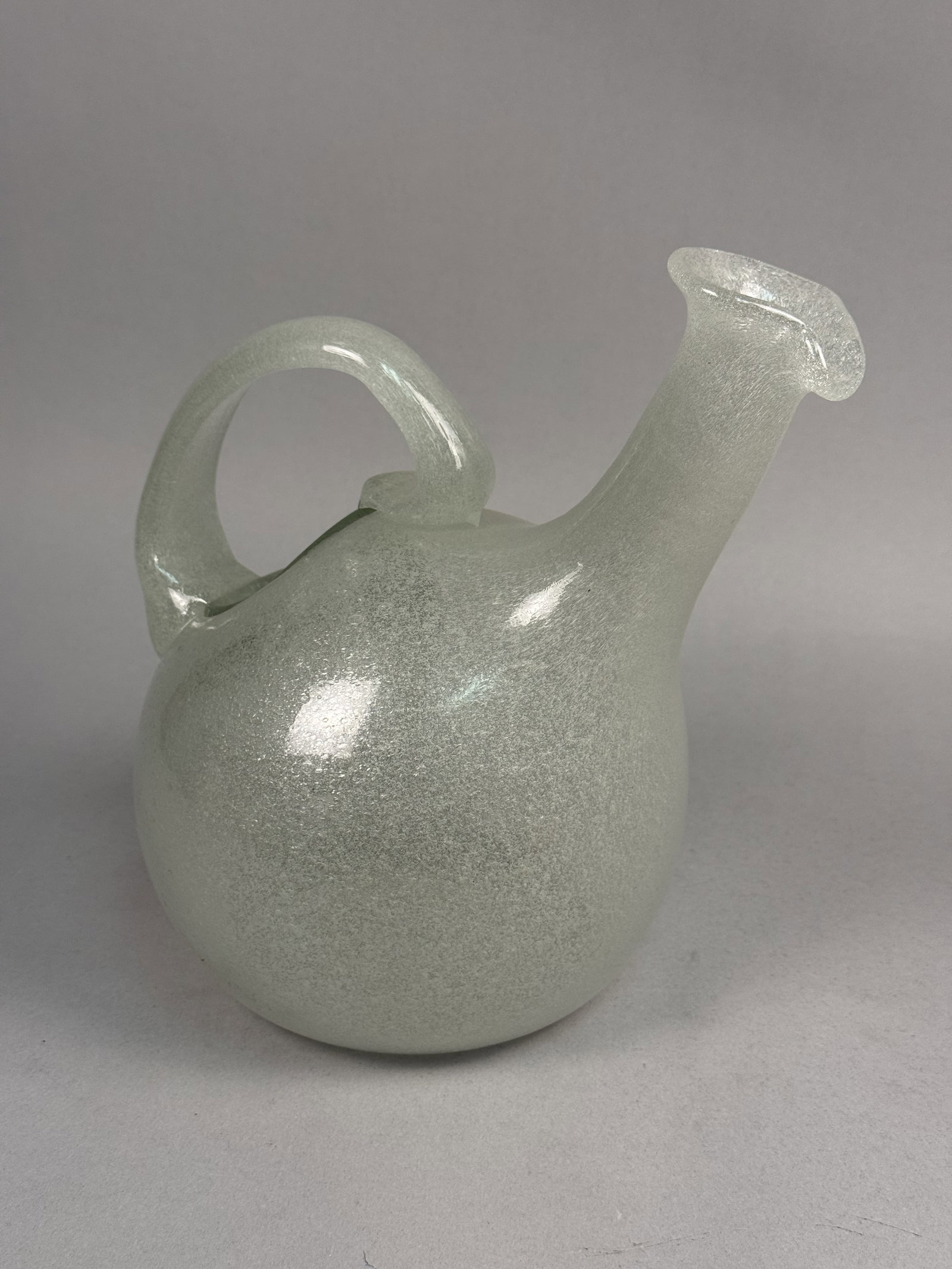 Murano Flavio Poli Pulegoso Pitcher: This hand-blown Murano glass pitcher was designed by Flavio Poli for Seguso Vetri d'Arte in the form of a traditional porron. The vessel is executed in pale aqua glass with a heavy pulegoso effect, cr