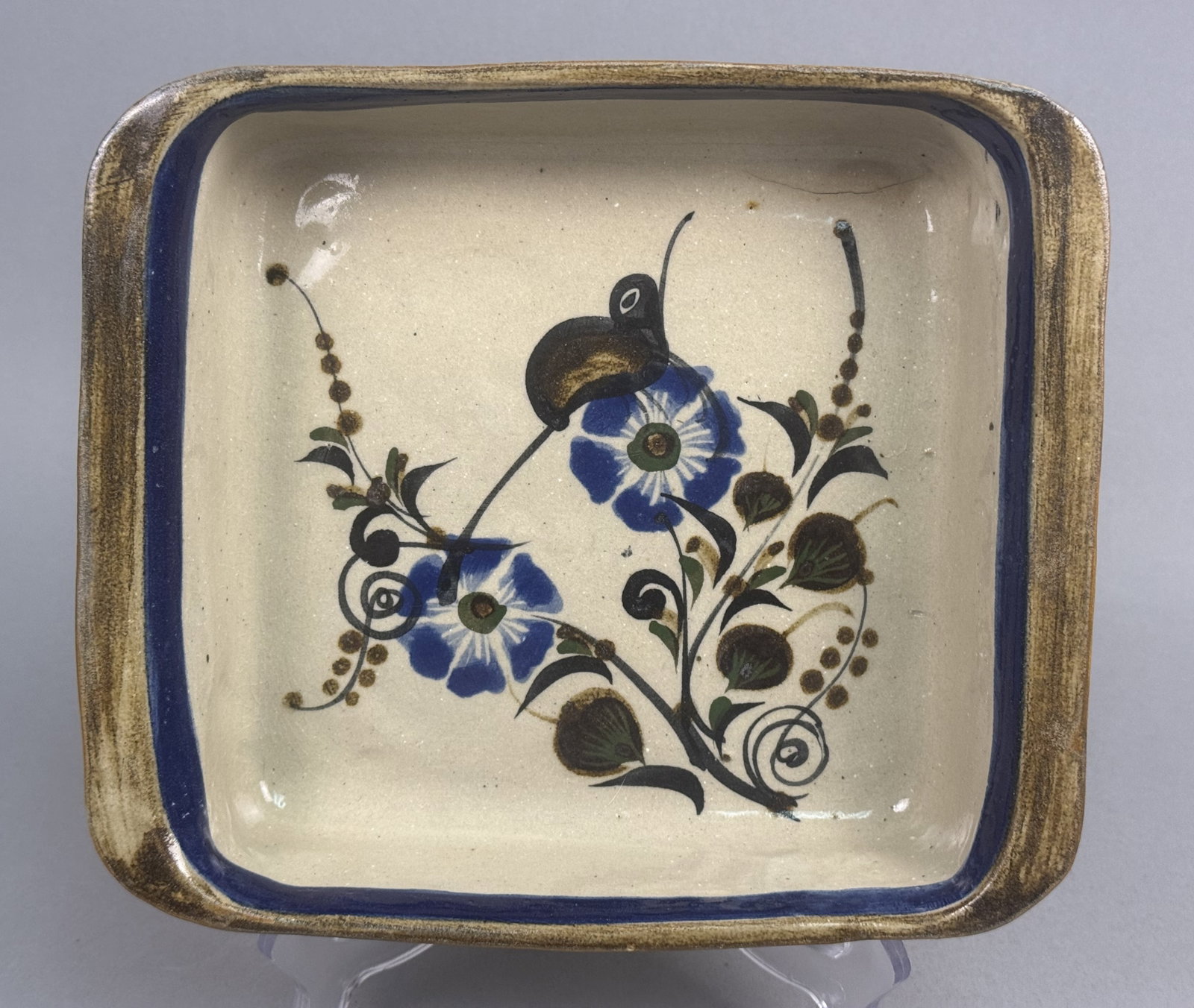 Ken Edwards El Palomar Stoneware Dish: A square Tonala stoneware baking dish from the El Palomar workshop featuring hand-painted folk art decoration. The interior depicts a stylized bird amongst botanical scrolls and flowers in blue and