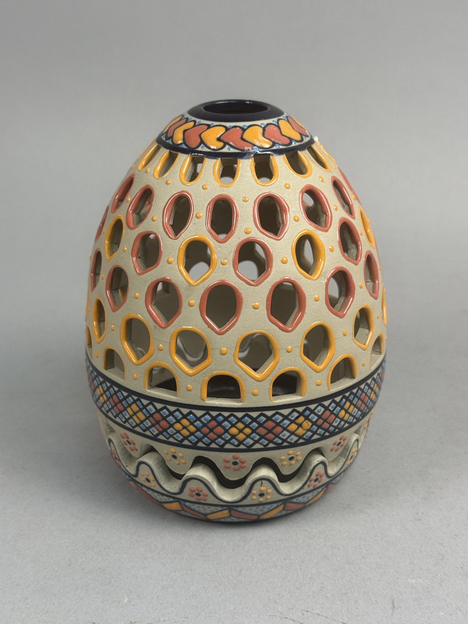 Servin Mexico Reticulated Stoneware Egg: A two-piece reticulated stoneware egg produced by the Servin studio in Mexico. The vessel features a hand-pierced cover and a matching base with a scalloped rim, decorated with intricate geometric