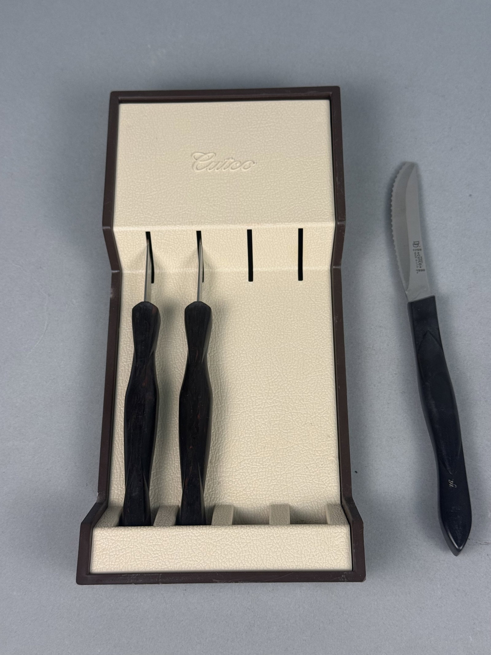 Trio of Vintage Cutco Table Knives: This lot features a trio of vintage Cutco model 1759 table knives with signature Double-D serrated stainless steel blades. The blades are tang-stamped 1990 and fitted with dark brown ergonomic