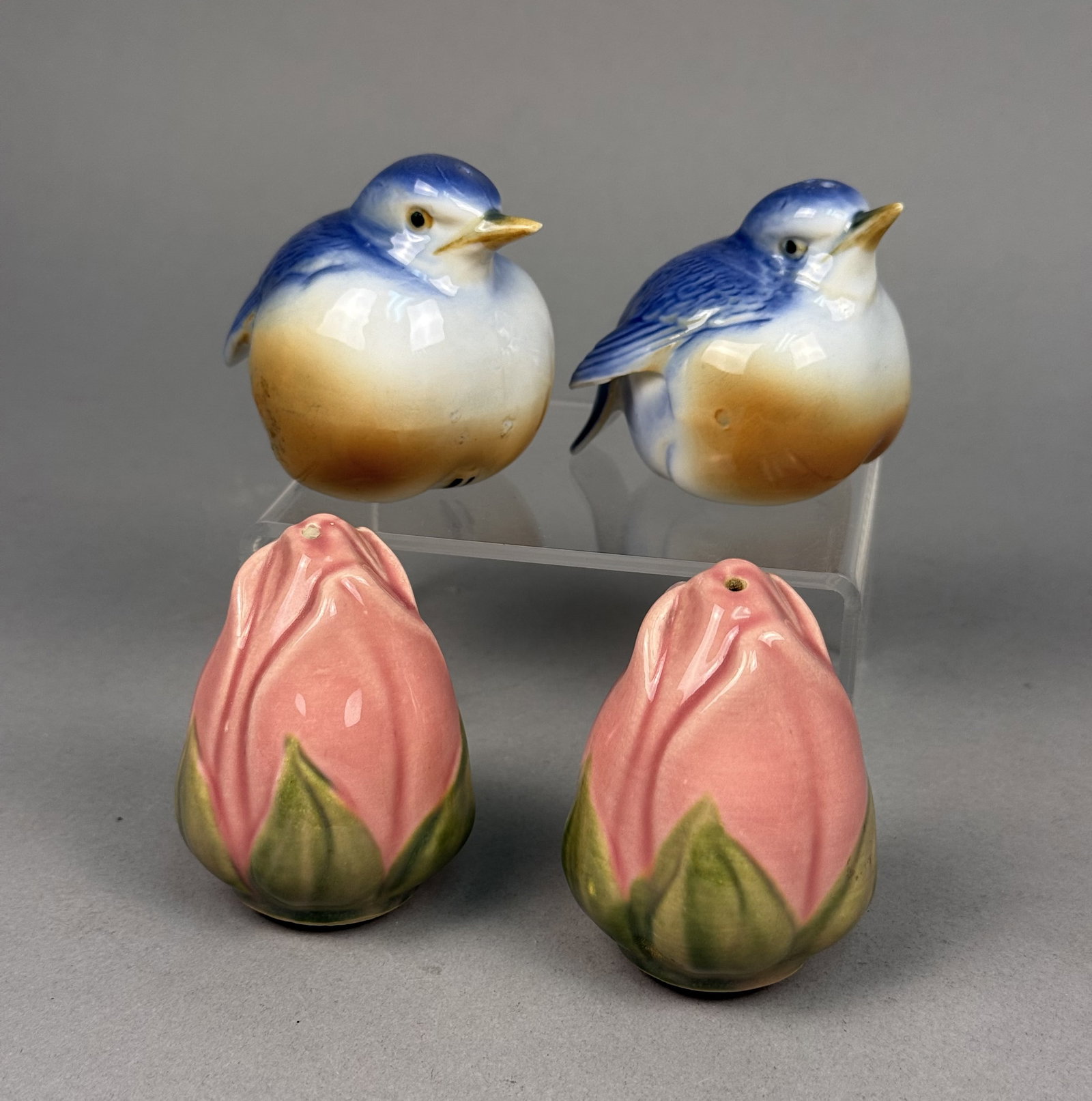 A Set of Vintage Figural Shakers: An assortment of vintage glazed ceramic salt and pepper shakers featuring avian and botanical motifs. The collection comprises rotund bluebirds with multicolored plumage and upright rosebuds in a