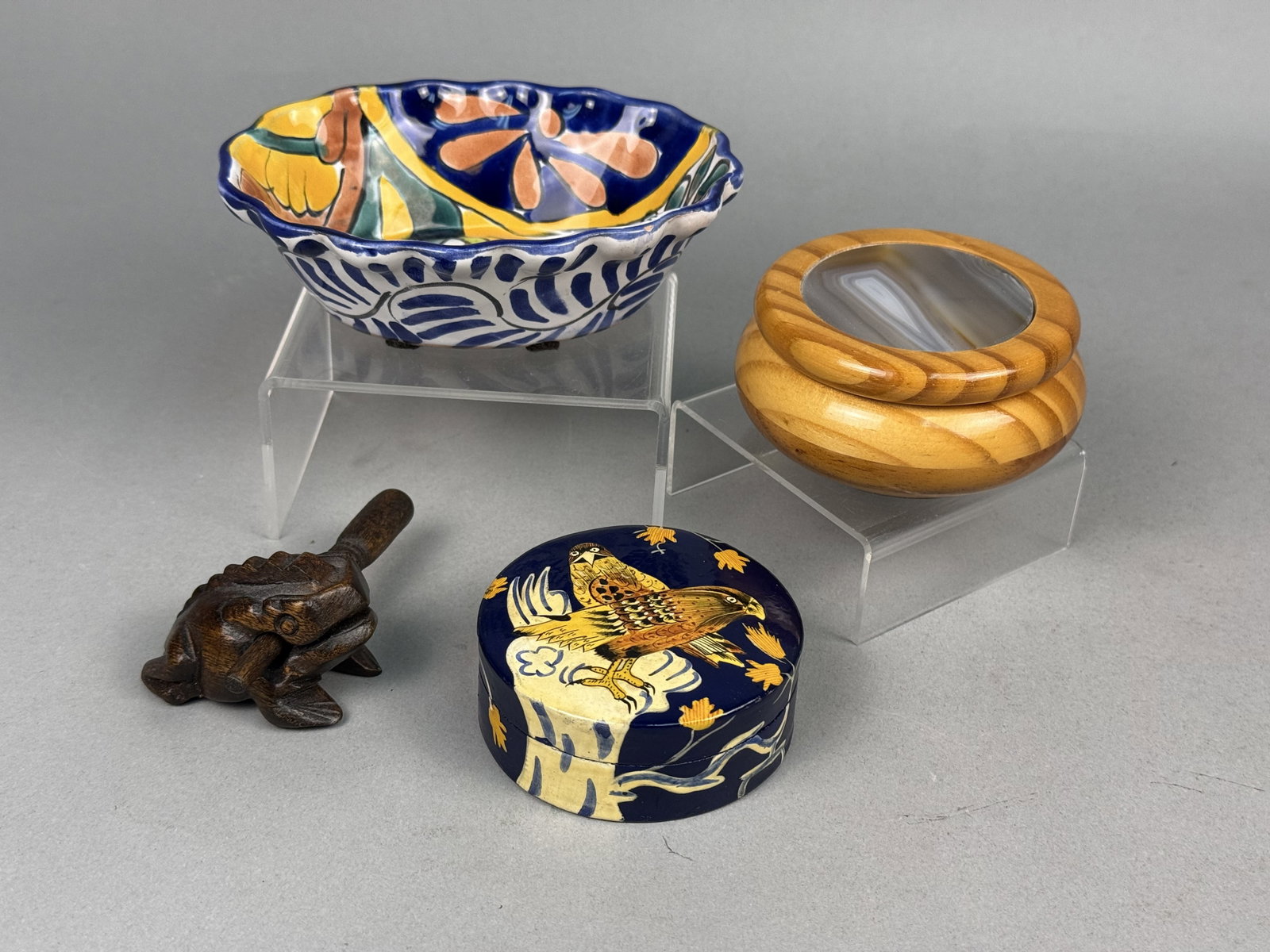 A Collection of Global Decorative Wares: This group includes a hand-painted Mexican Talavera ceramic bowl, a Brazilian turned wood box with a polished agate lid, a Kashmiri papier-mache box, and a carved wooden frog percussion instrument. Th