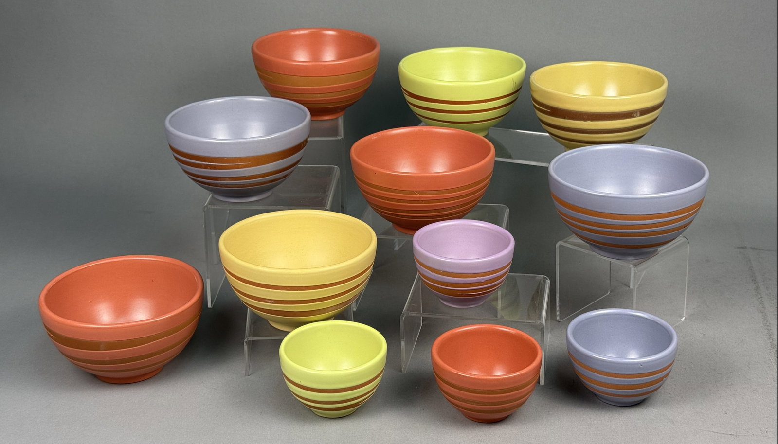Twelve Starbucks Multi-Colored Striped Bowls: A set of twelve ceramic bowls manufactured for Starbucks Coffee Company featuring a matte finish and horizontal bands. The group consists of four graduated sizes in coordinated shades of terracotta,