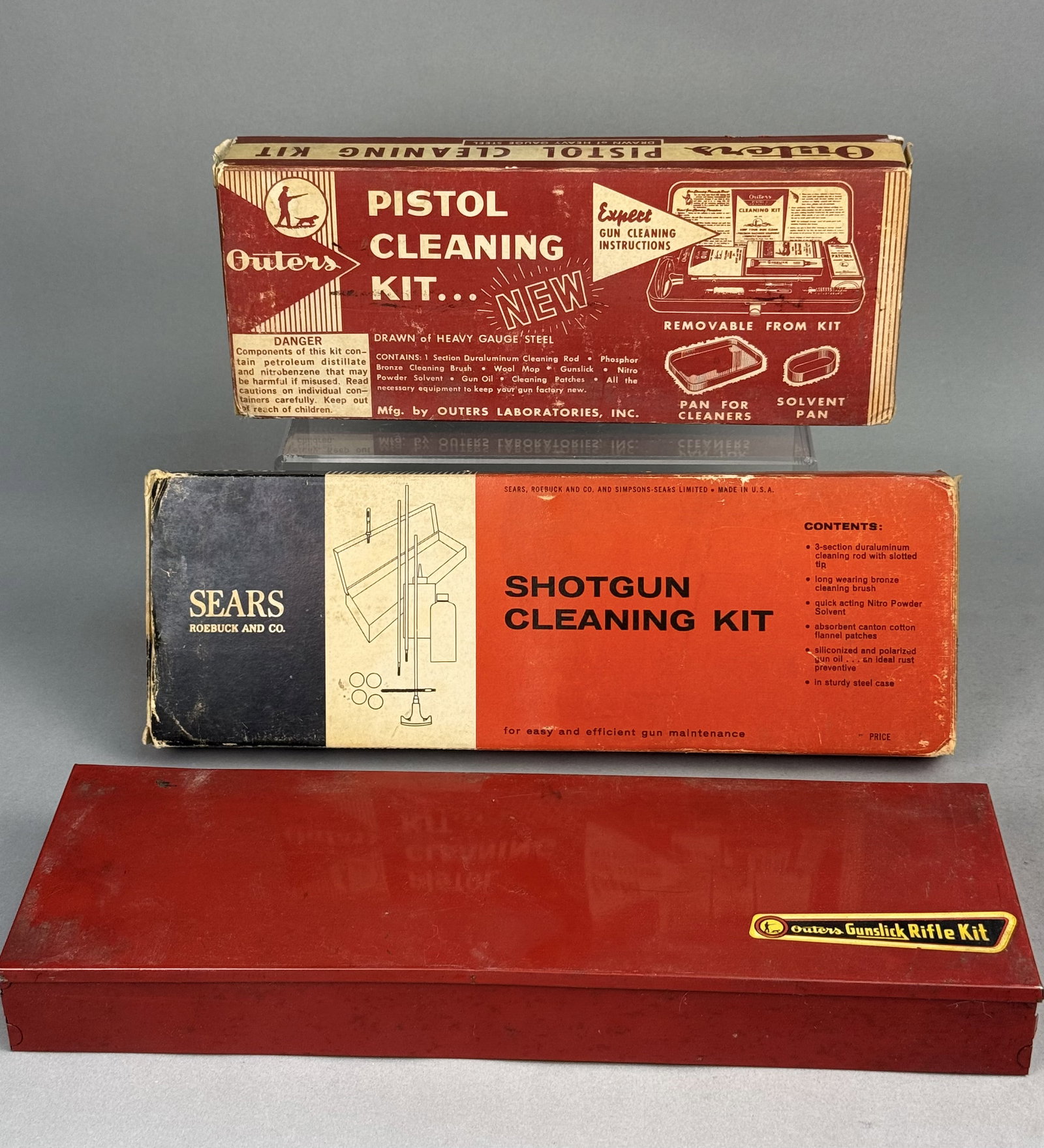 An Assortment of Gun Cleaning Kits: A collection of vintage gun cleaning kits, comprising an Outers Pistol and Revolver Kit No. 479, a Sears, Roebuck and Co. Shotgun Cleaning Kit No. 20221, and an Outers Gunslick Rifle Kit. Each unit