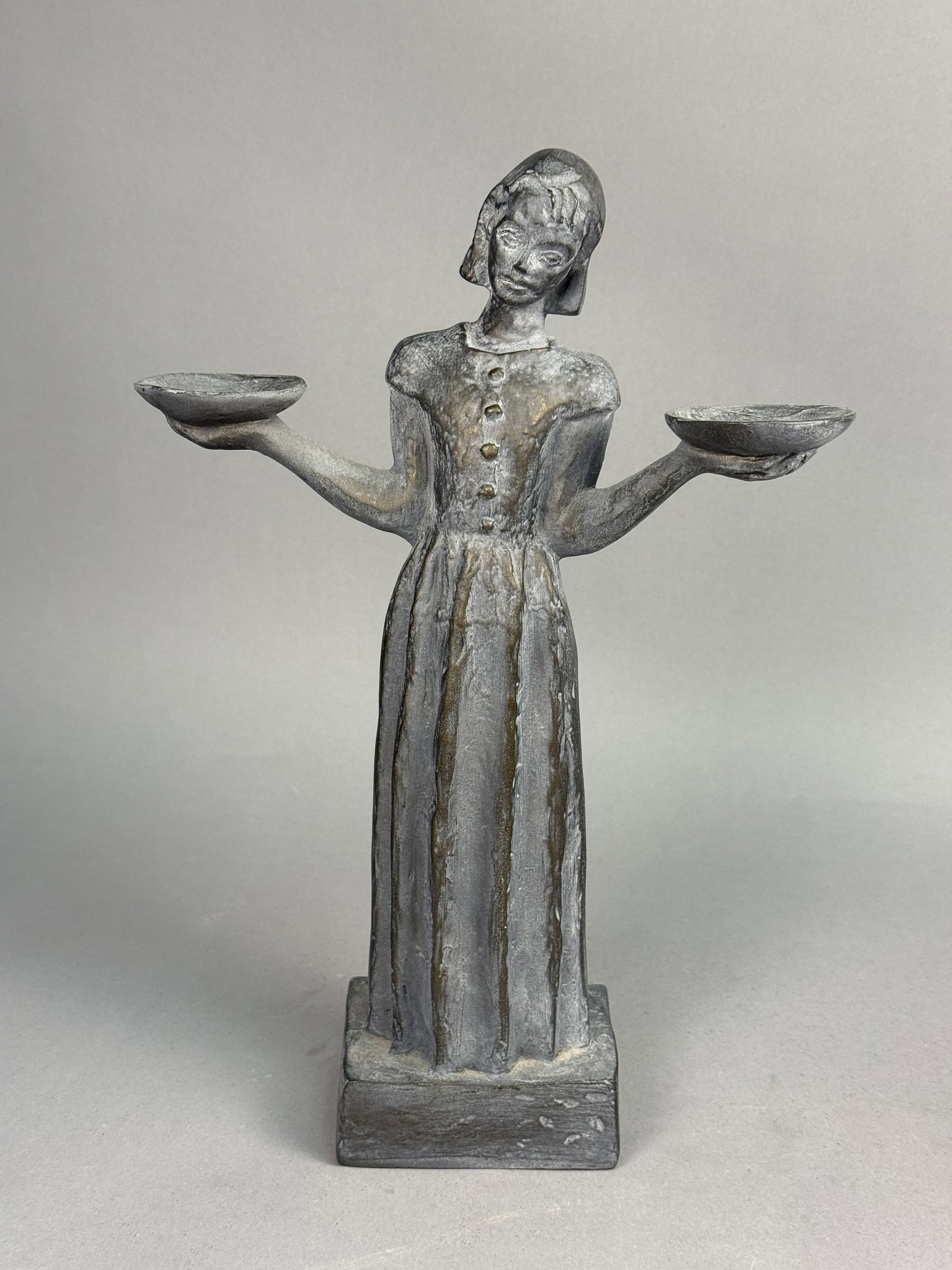 Sylvia Shaw Judson Bird Girl Statue: This cast composite sculpture depicts the Bird Girl, a model originally designed by Sylvia Shaw Judson in 1936. The figure is finished with a dark grey and golden-bronze faux patina over a