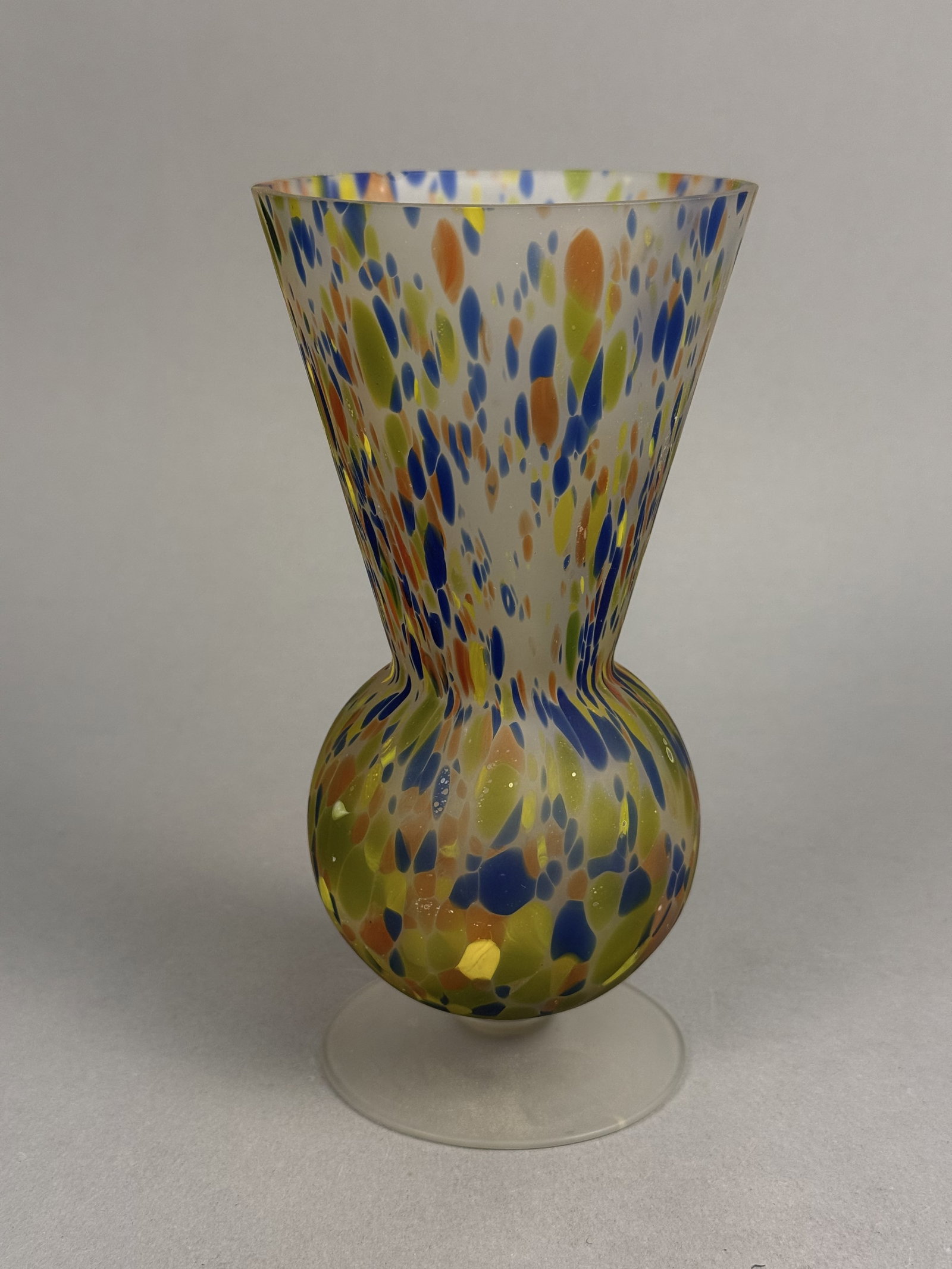 Hand-Blown Confetti Glass Pedestal Vase: This hand-blown art glass vase features a multi-color confetti spatter design in shades of cobalt blue, chartreuse, and orange. The vessel is formed with a wide flared rim and a bulbous lower body sup