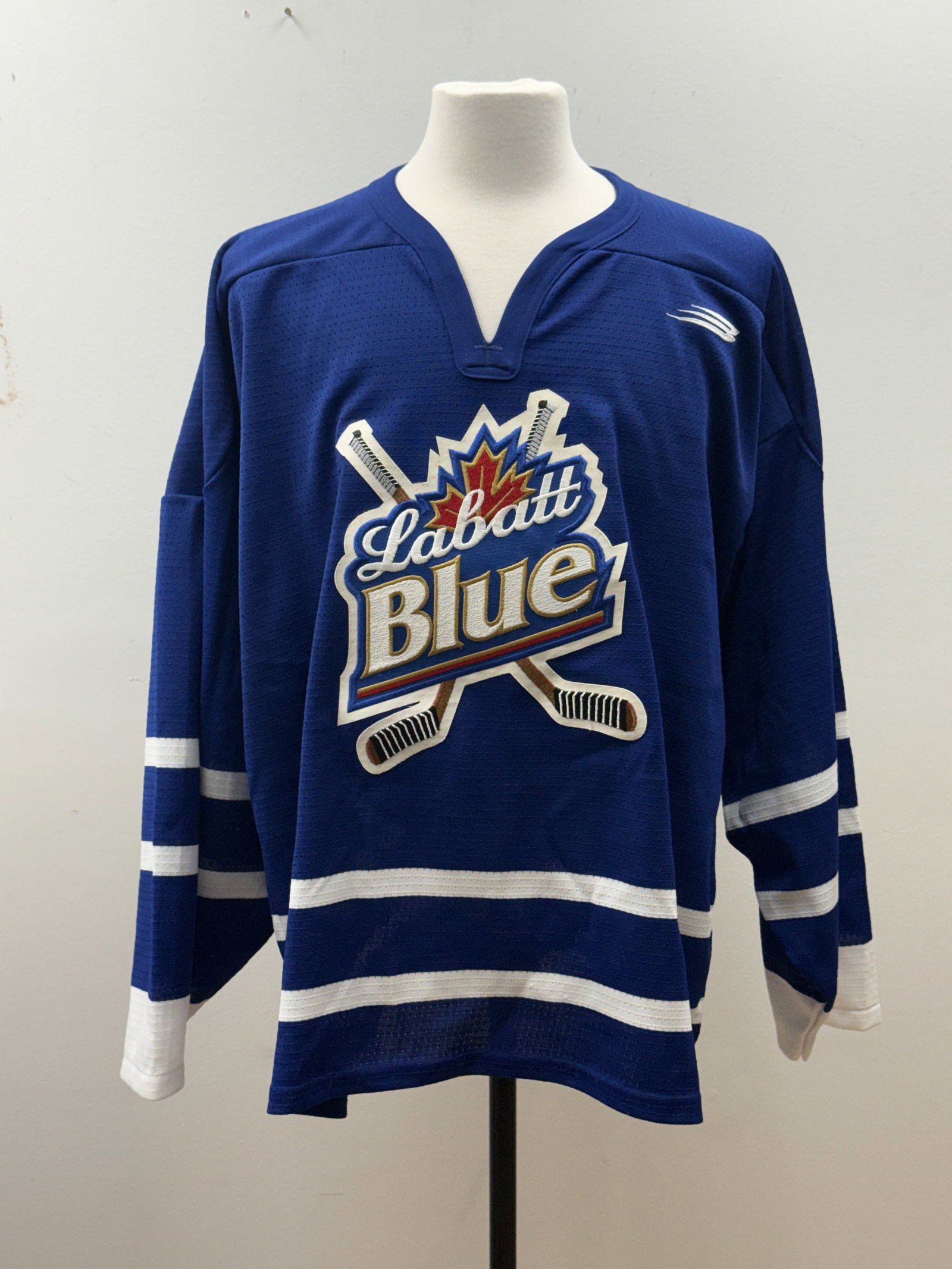 Bauer Labatt Blue Hockey Jersey: A promotional blue mesh hockey jersey by Bauer featuring the Labatt Blue beer logo embroidered as a large central crest. The garment is constructed of 100 percent polyester with white contrast