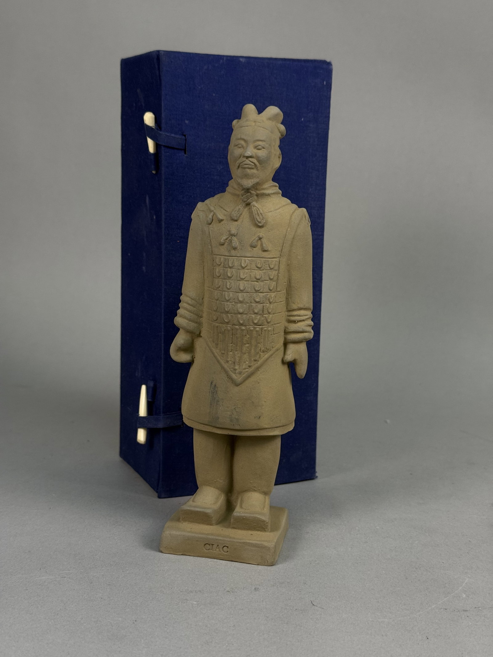 CIAC Miniature Terracotta Warrior and Box: Produced by the China International Advertising Corp (CIAC), this miniature terracotta-colored ceramic figurine depicts an armored general from the Terracotta Army. The figure is modeled with a