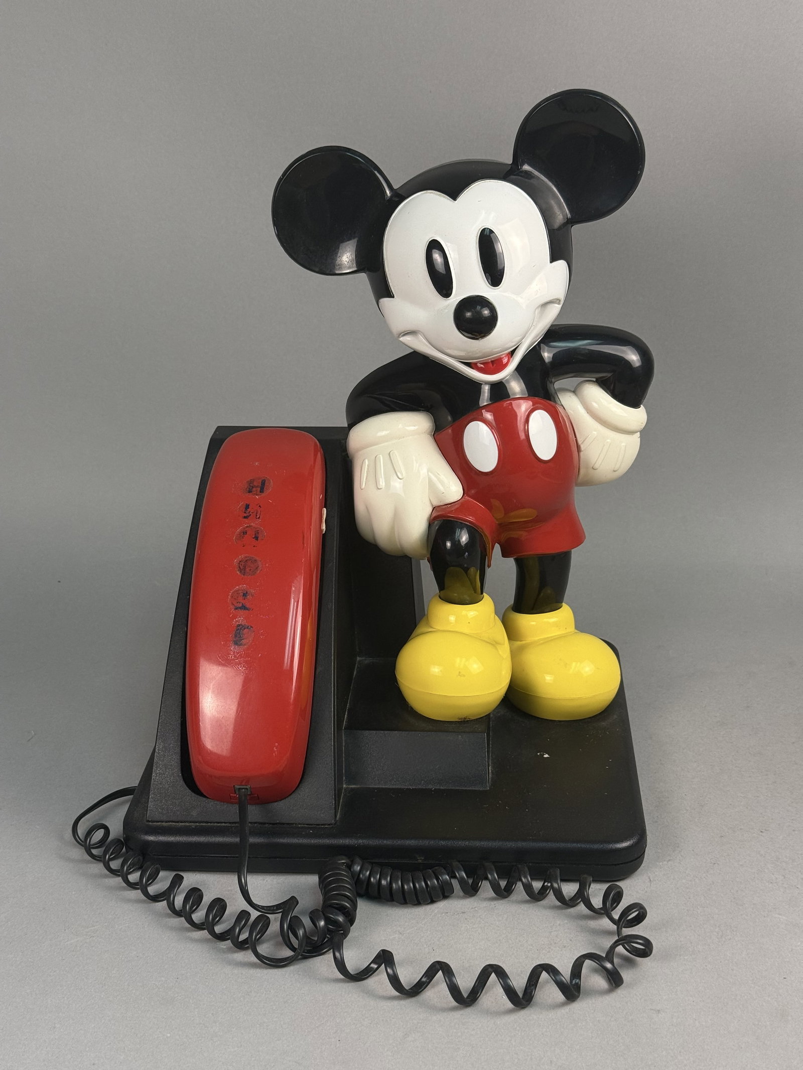 AT&T Mickey Mouse Character Telephone: This vintage AT&T novelty telephone, model CS2881D109, features a three-dimensional molded plastic Mickey Mouse figure leaning against a black wedge-shaped base. The unit includes a red corded handset