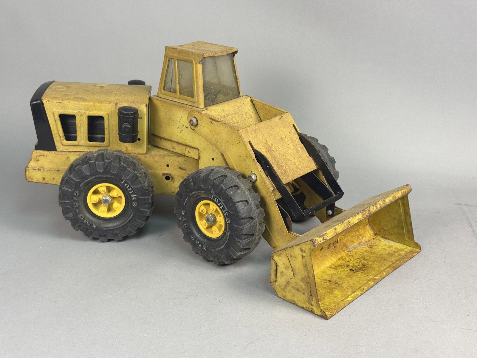 Tonka Mighty Front End Loader: This Tonka Mighty Diesel front-end loader is constructed of pressed steel with an articulated central steering joint and a manually operated lifting bucket. The toy features plastic components includi